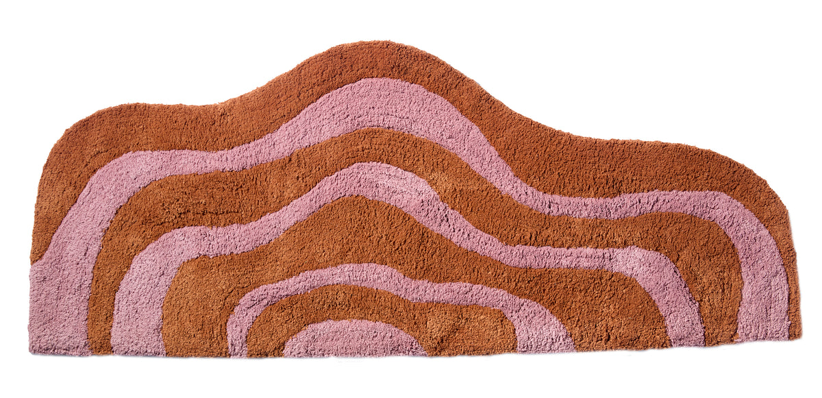 Wave shaped honey and rose striped bath mat runner in 56"x22" size with white background.