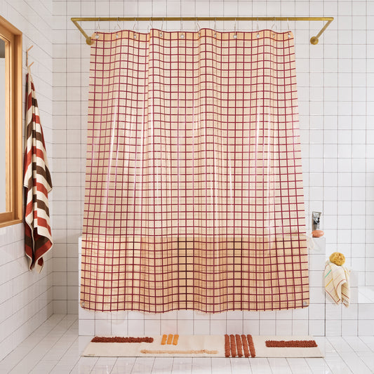 Checkered shower curtain in a bathroom with tiled walls and a bath mat on the floor.
