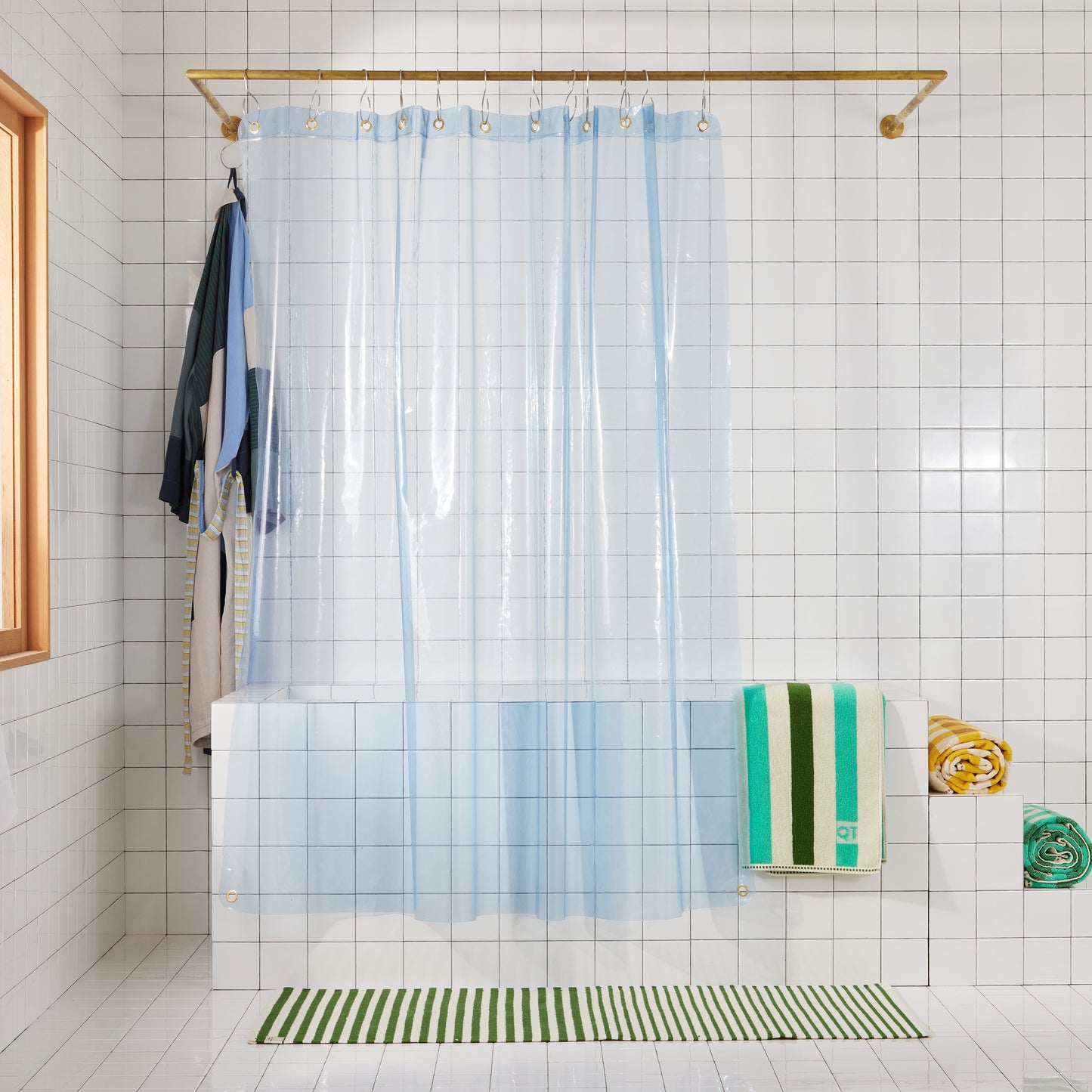transparent blue shower curtain hanging in white bathroom