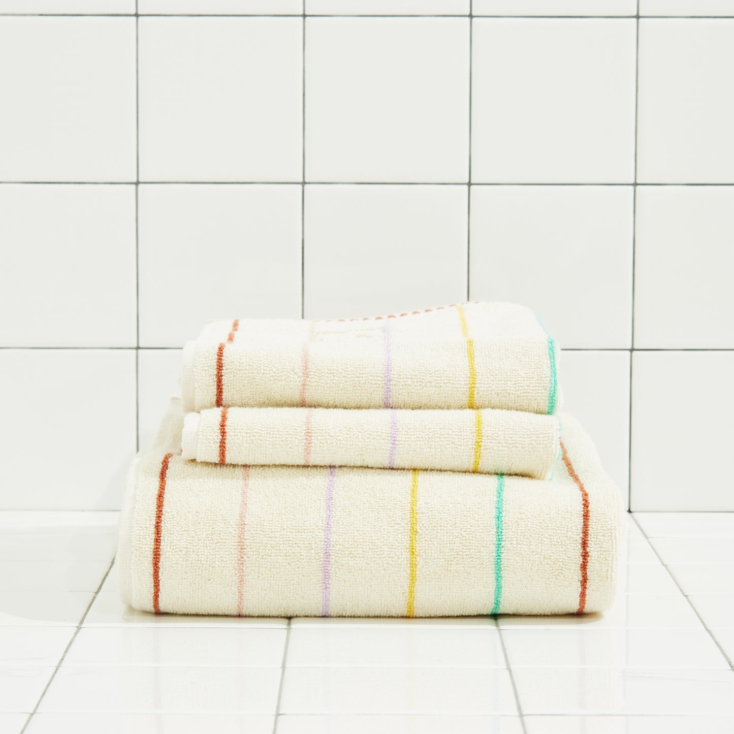 Stack of folded towels with colorful stripes on a tiled floor