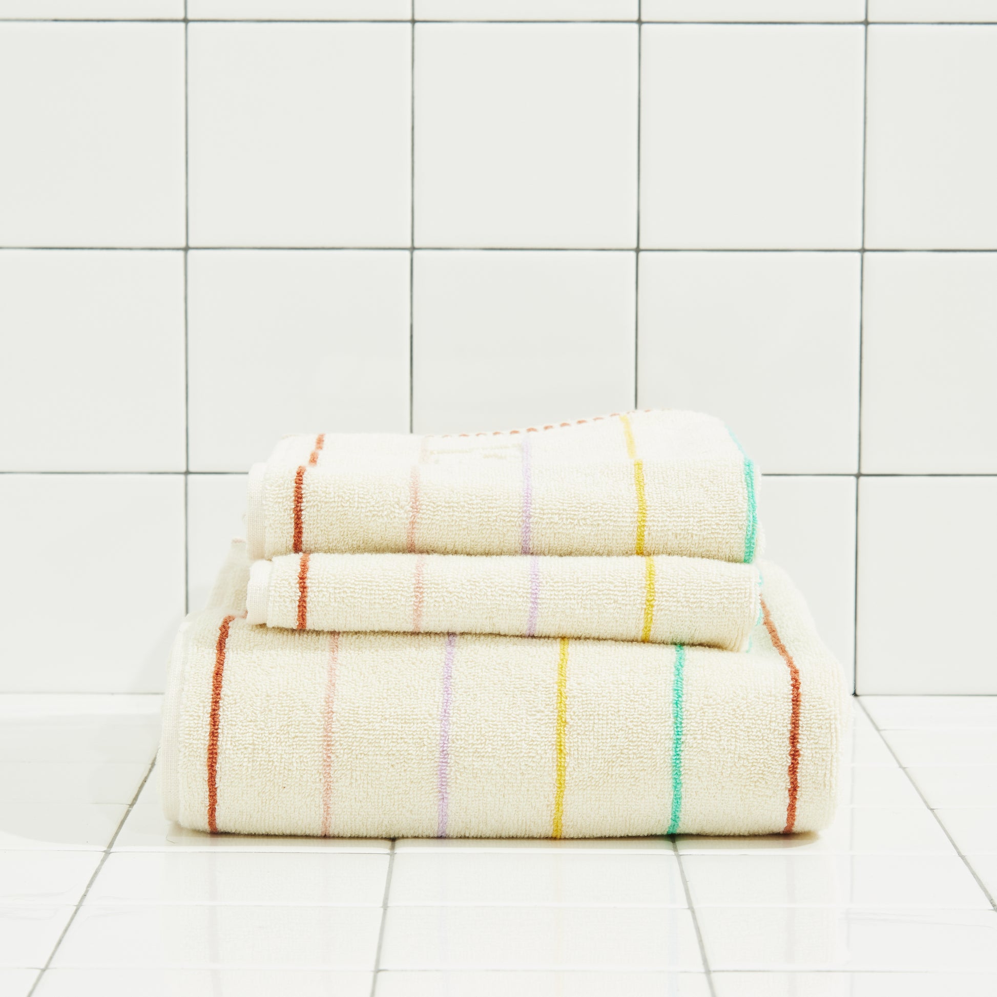 Stack of folded towels with colorful stripes on a tiled floor