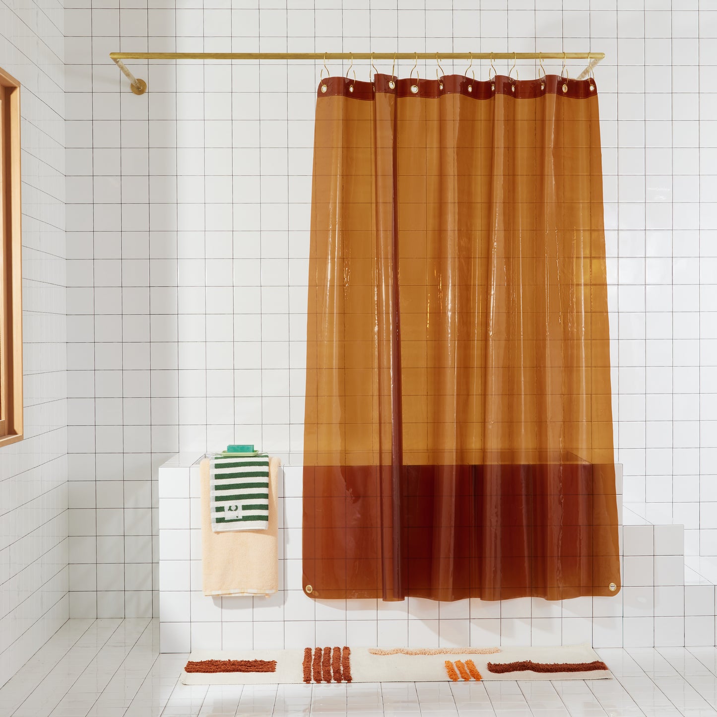 transparent amber shower curtain hanging in white bathroom.