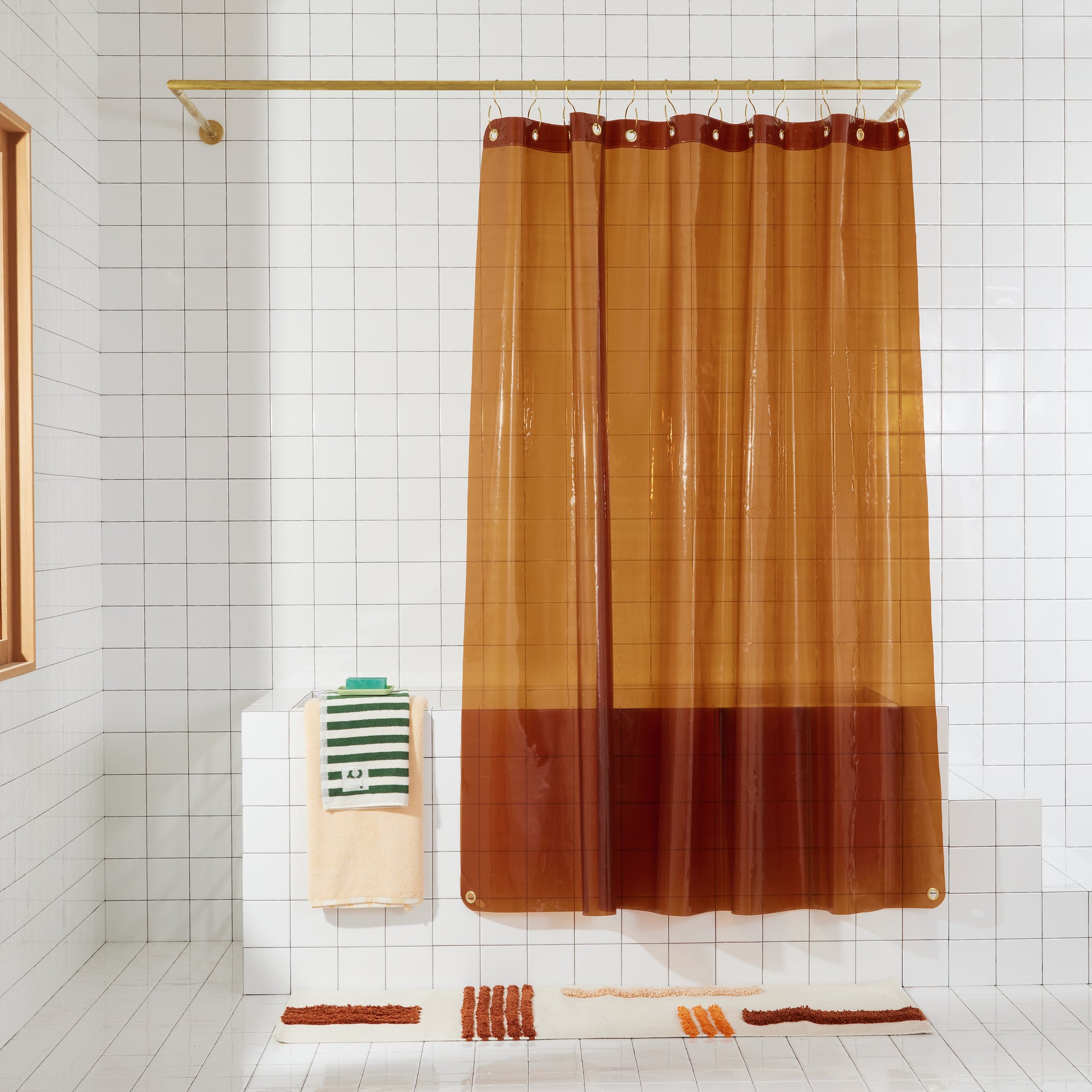 transparent amber shower curtain hanging in white bathroom.
