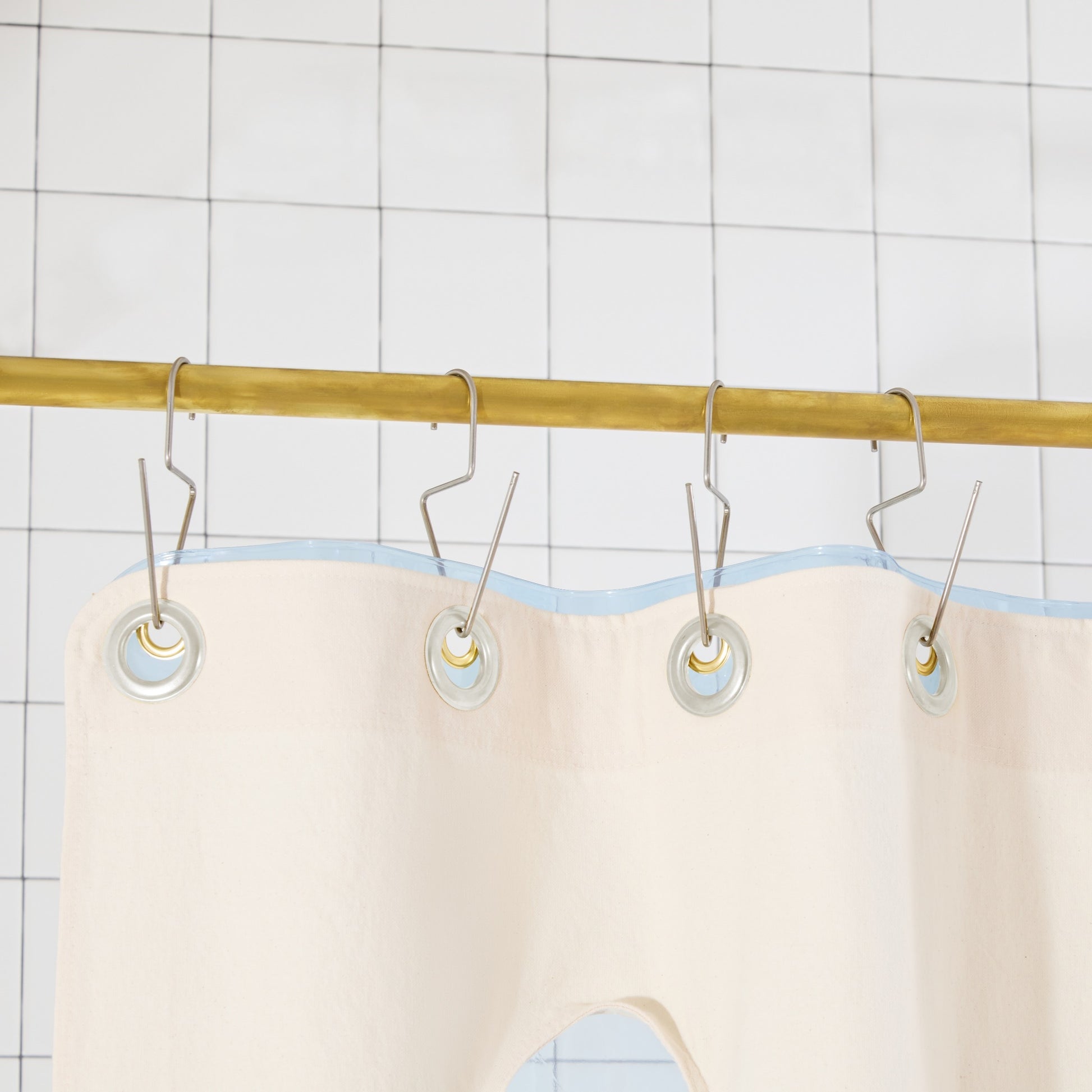 Bubble Pine detail view of grommets and hooks hanging from shower curtain rod.