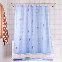 light blue shower curtain with cut outs in a white tiled bathroom and a blue patterned rug and a clay colored checkered towel.