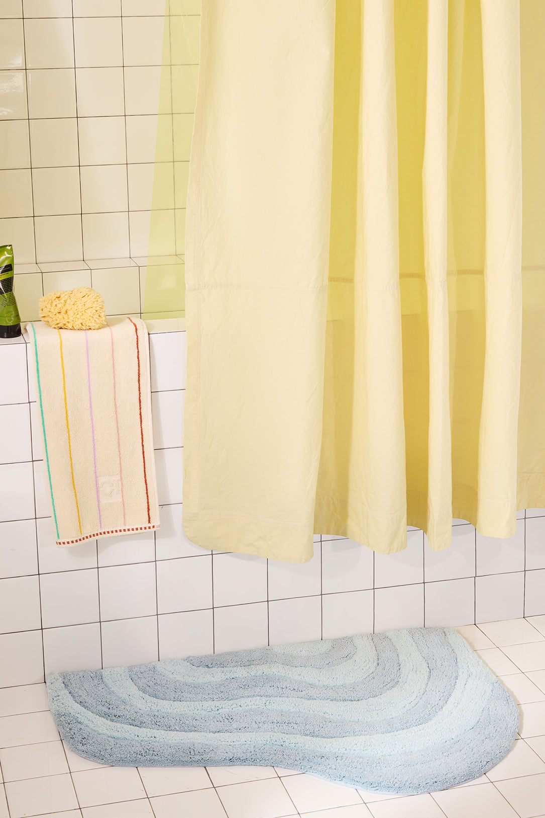 Bathroom with a yellow shower curtain, bath mat, and towel.