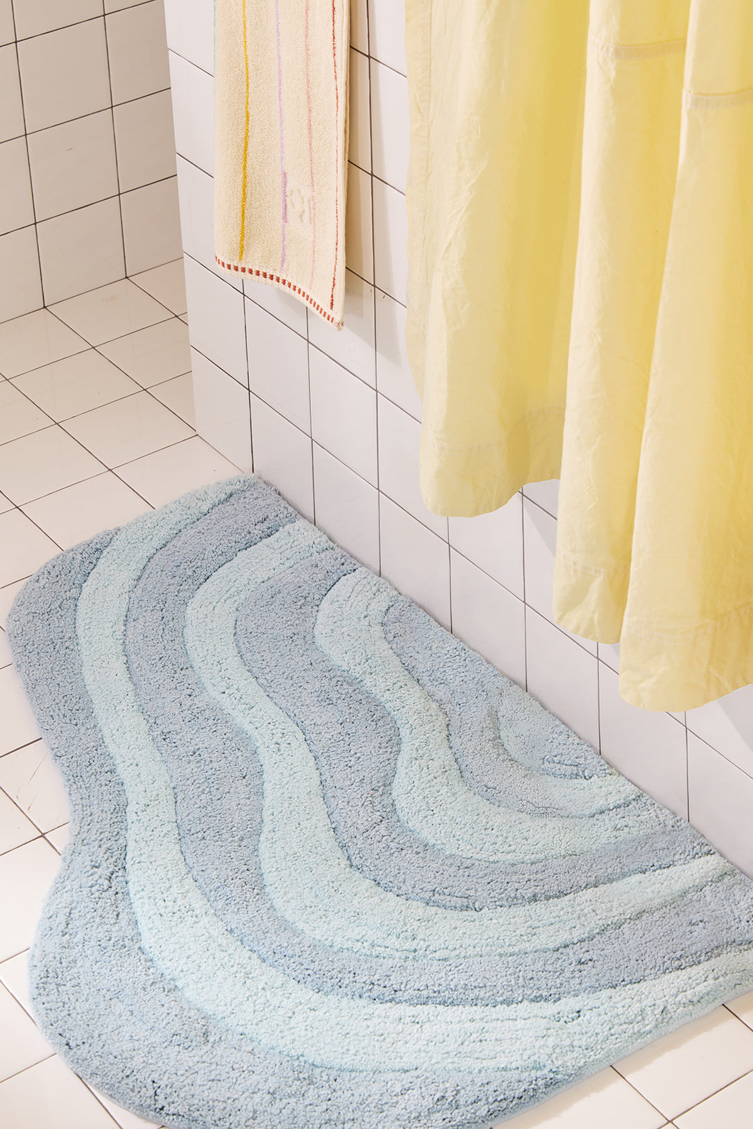 Bathroom with a textured blue rug on the floor and a yellow shower curtain.