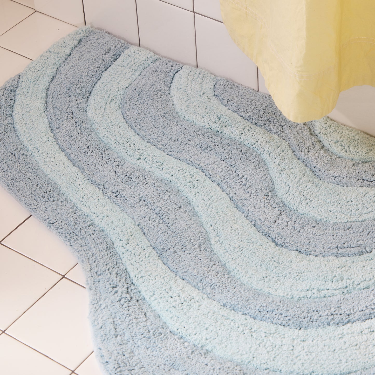 Wavy patterned bath mat on a tiled bathroom floor