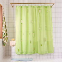 bright green shower curtain with cut outs in a white tiled bathroom.