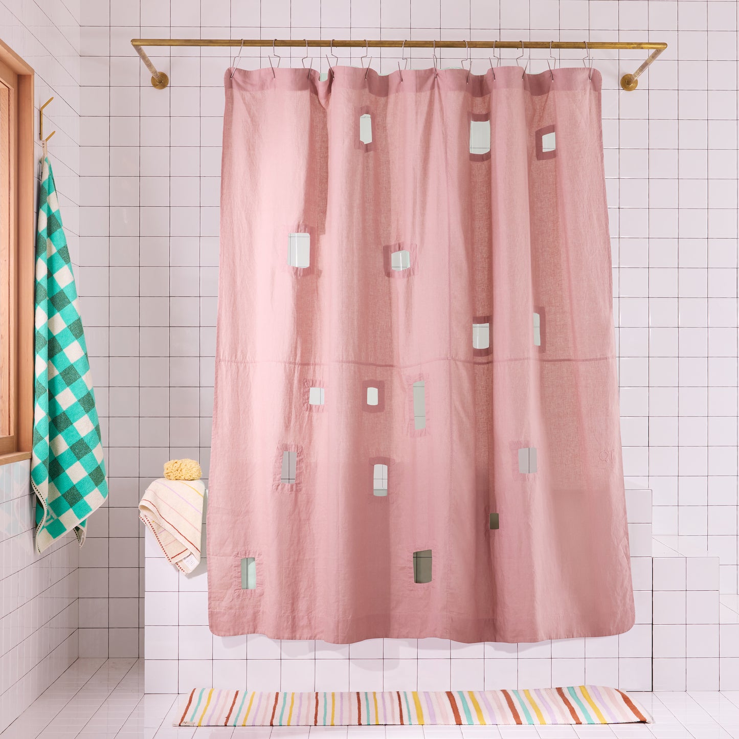 Pink shower curtain with geometric cut-outs in a white tiled bathroom.
