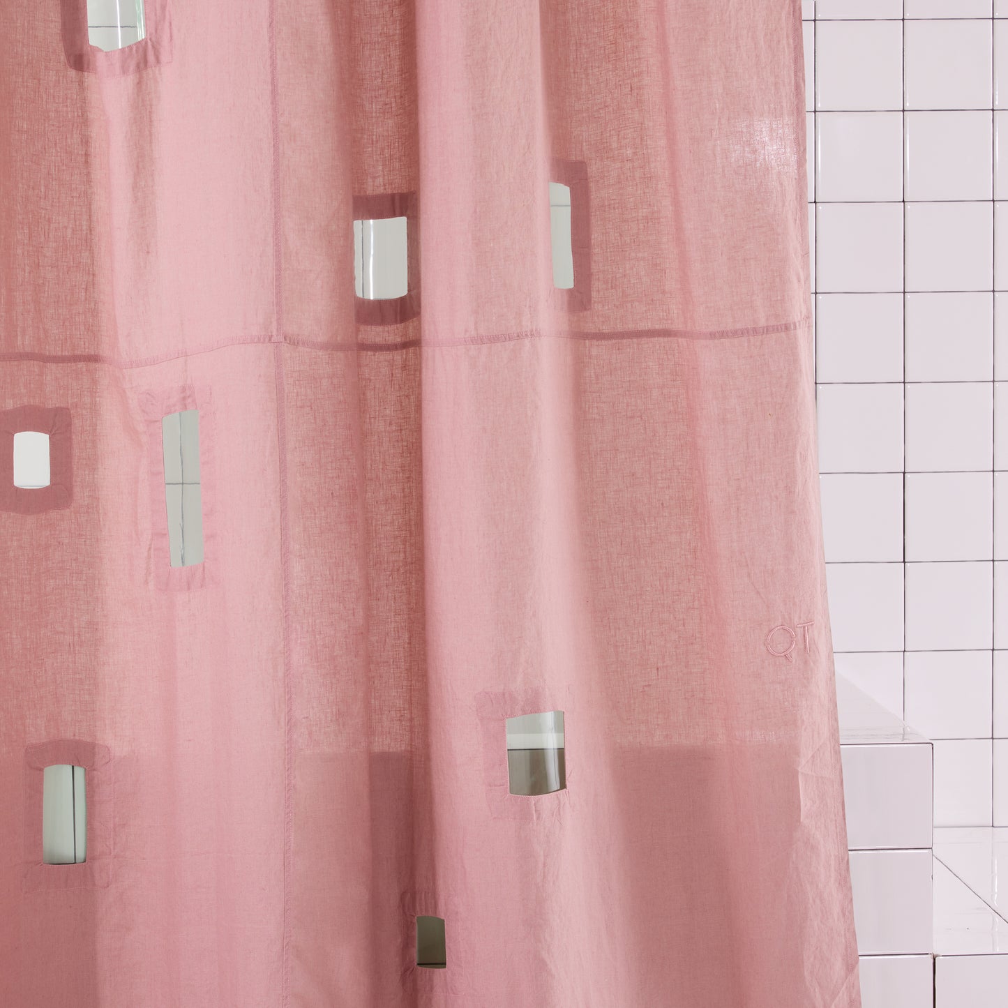 Pink shower curtain with geometric cut outs in a bathroom setting