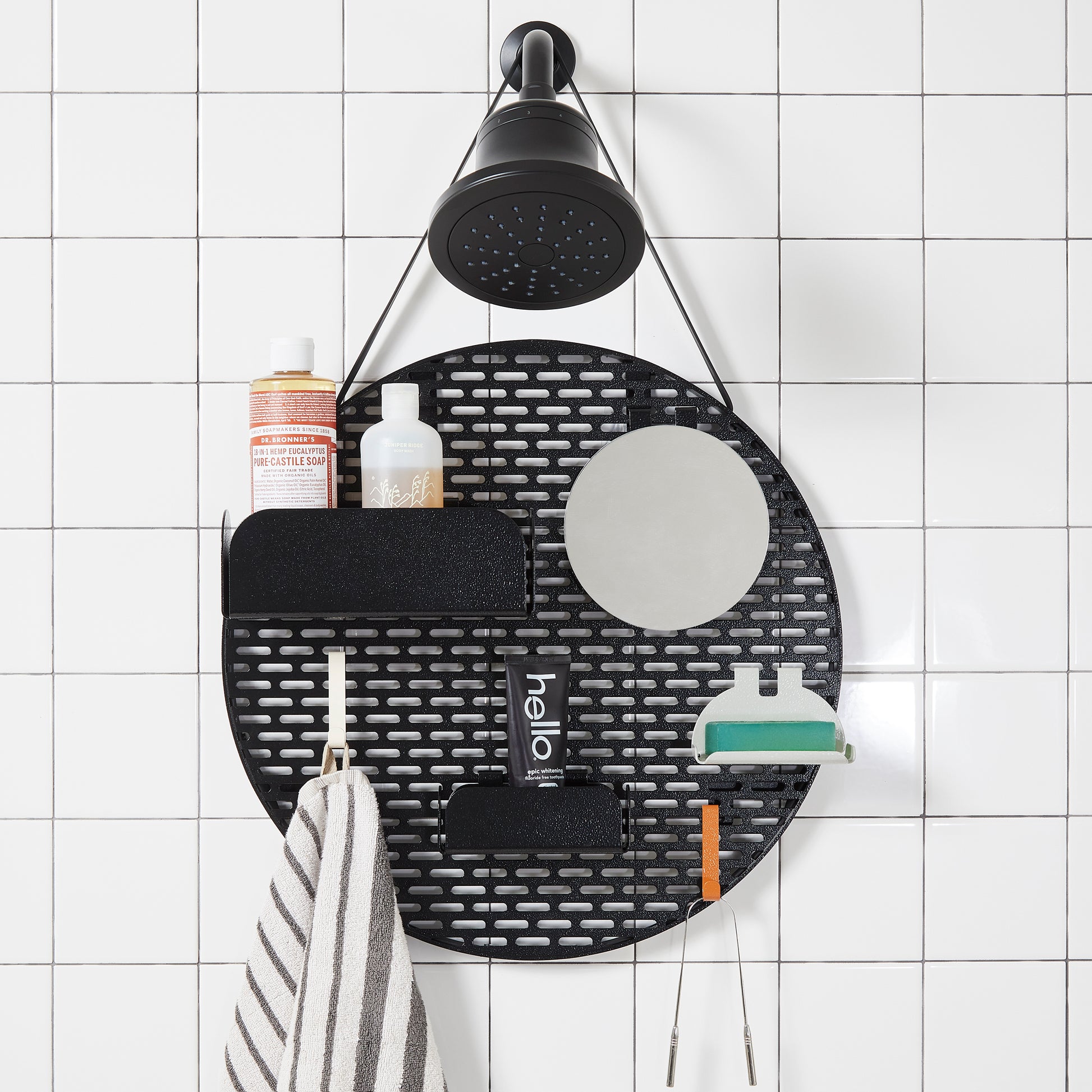 The spot modular shower organizer with shelving pieces arranged and holding products, hanging in a white tiled shower.