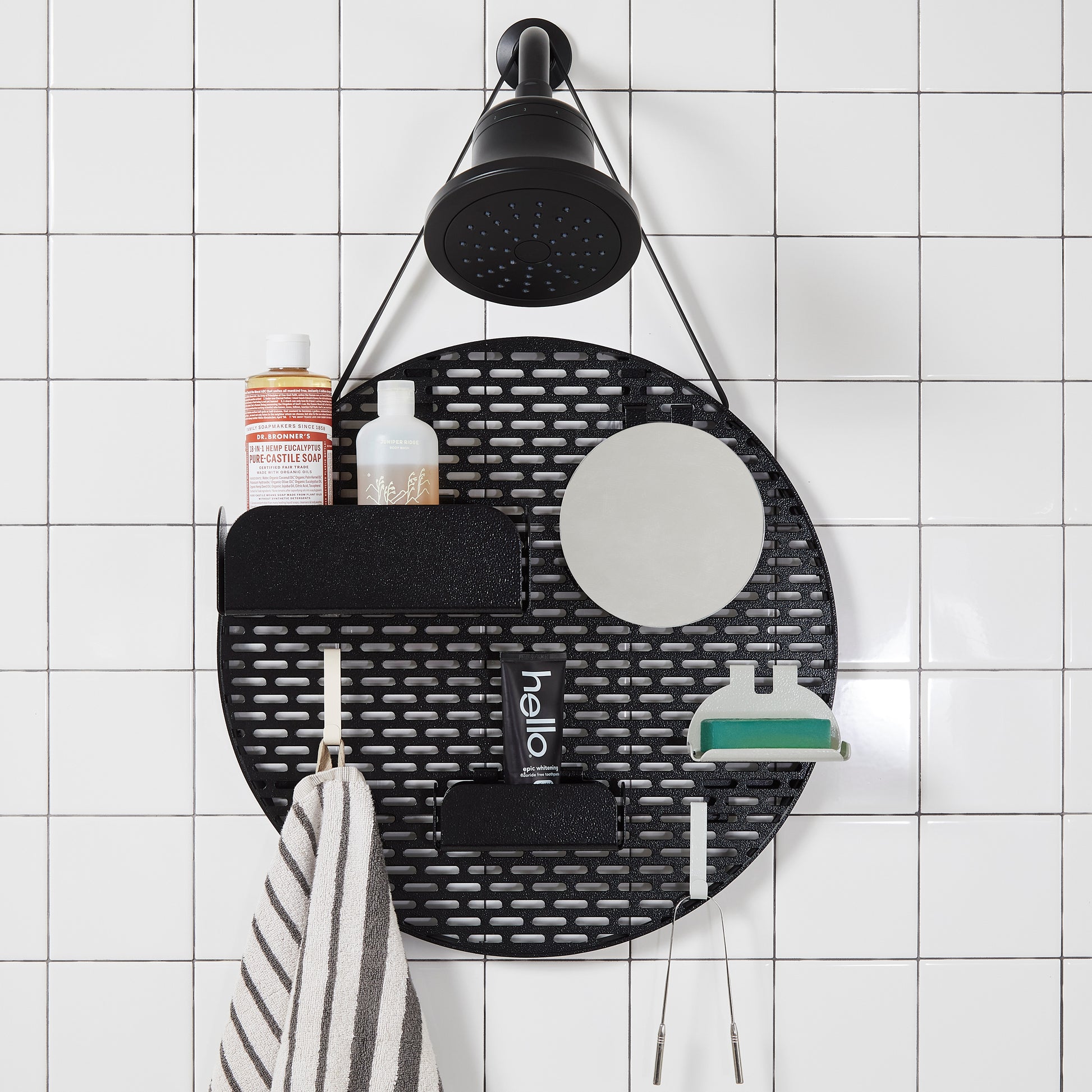 The spot modular shower organizer with shelving pieces arranged and holding products, hanging in a white tiled shower.