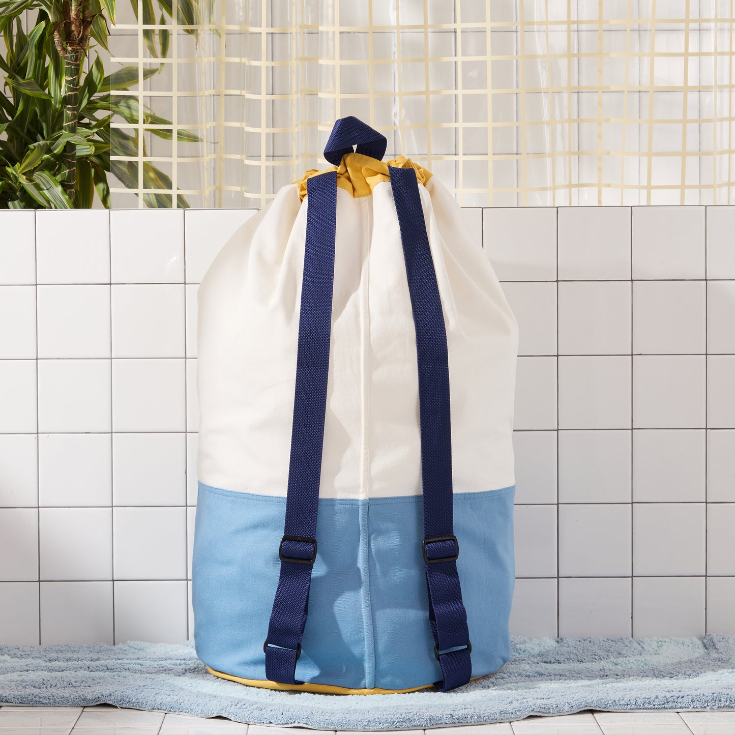 back of blue laundry bag with navy blue straps. 
