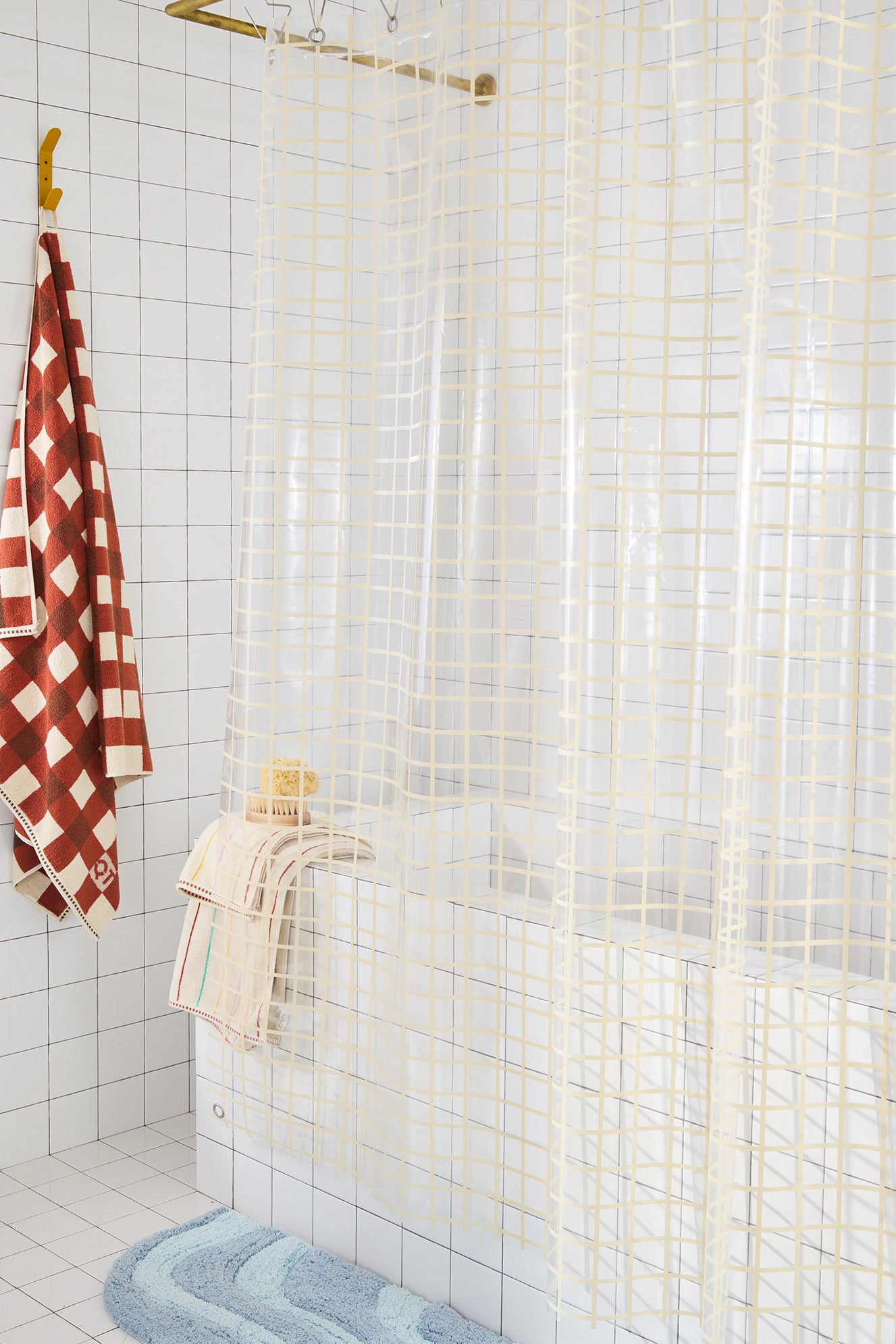 Bathroom with tiled walls, a shower curtain, and a towel hook with a red and white checkered towel.