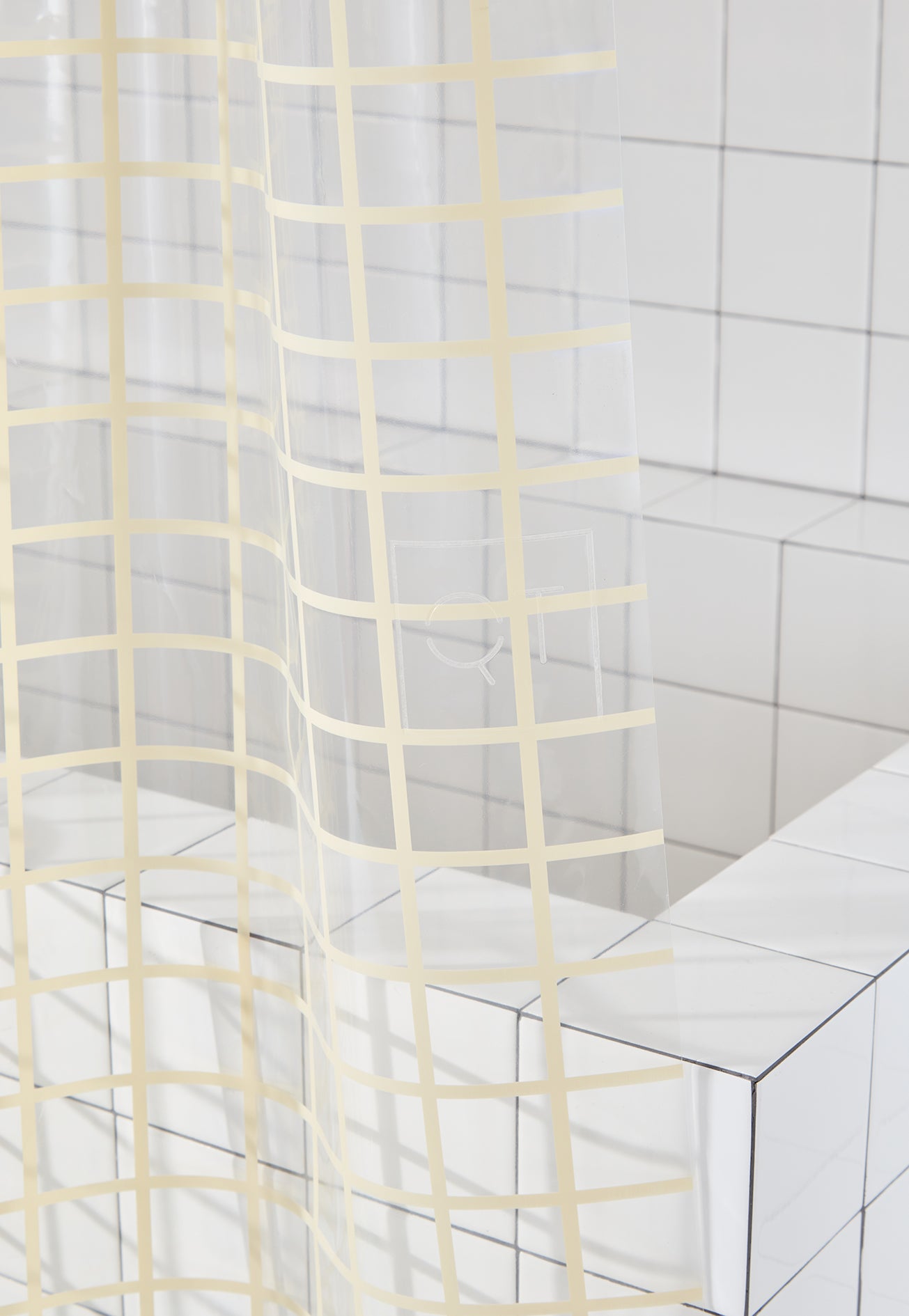 Clear shower curtain with cream grid pattern in a bathroom setting