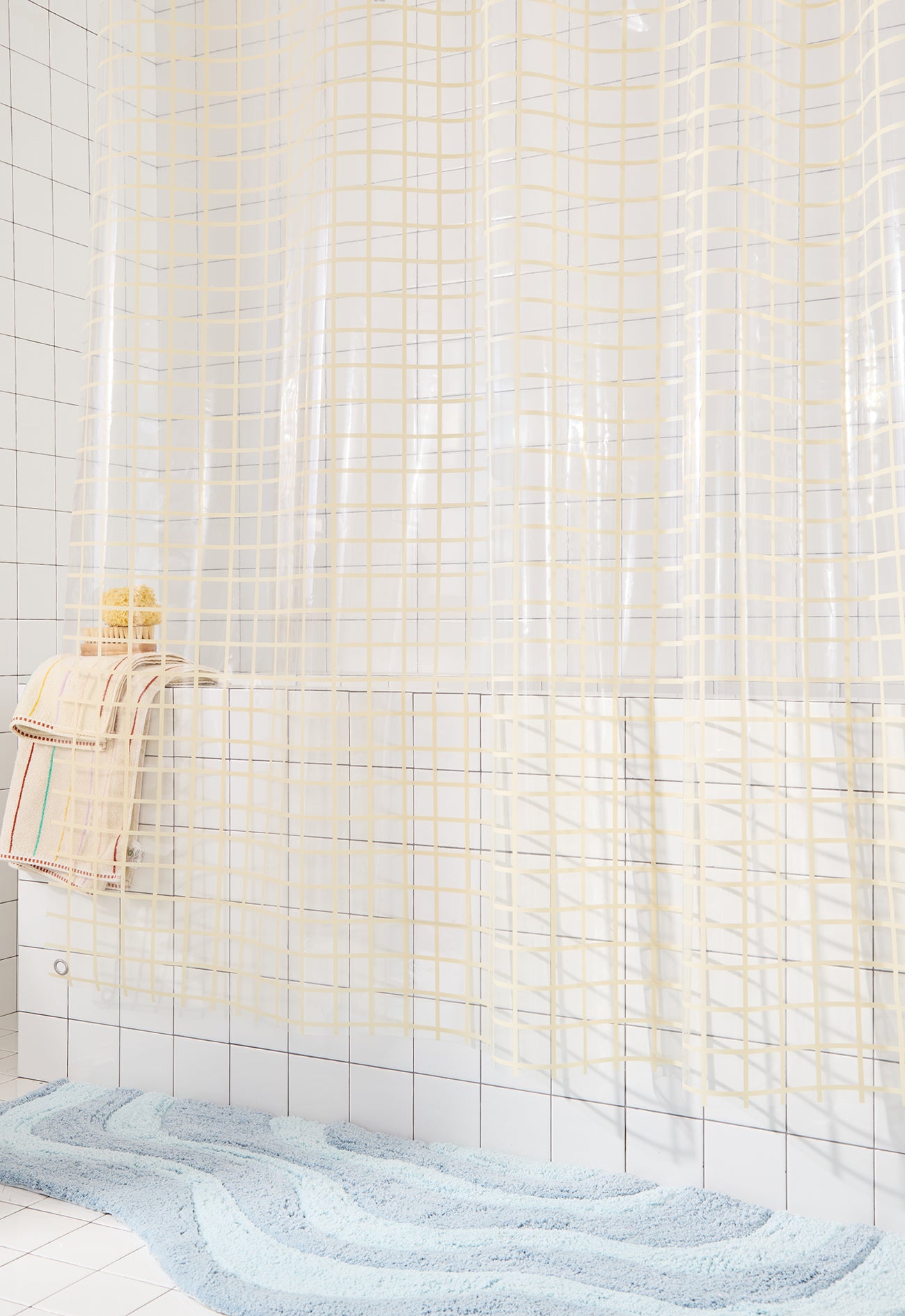 Shower curtain with grid pattern in a tiled bathroom