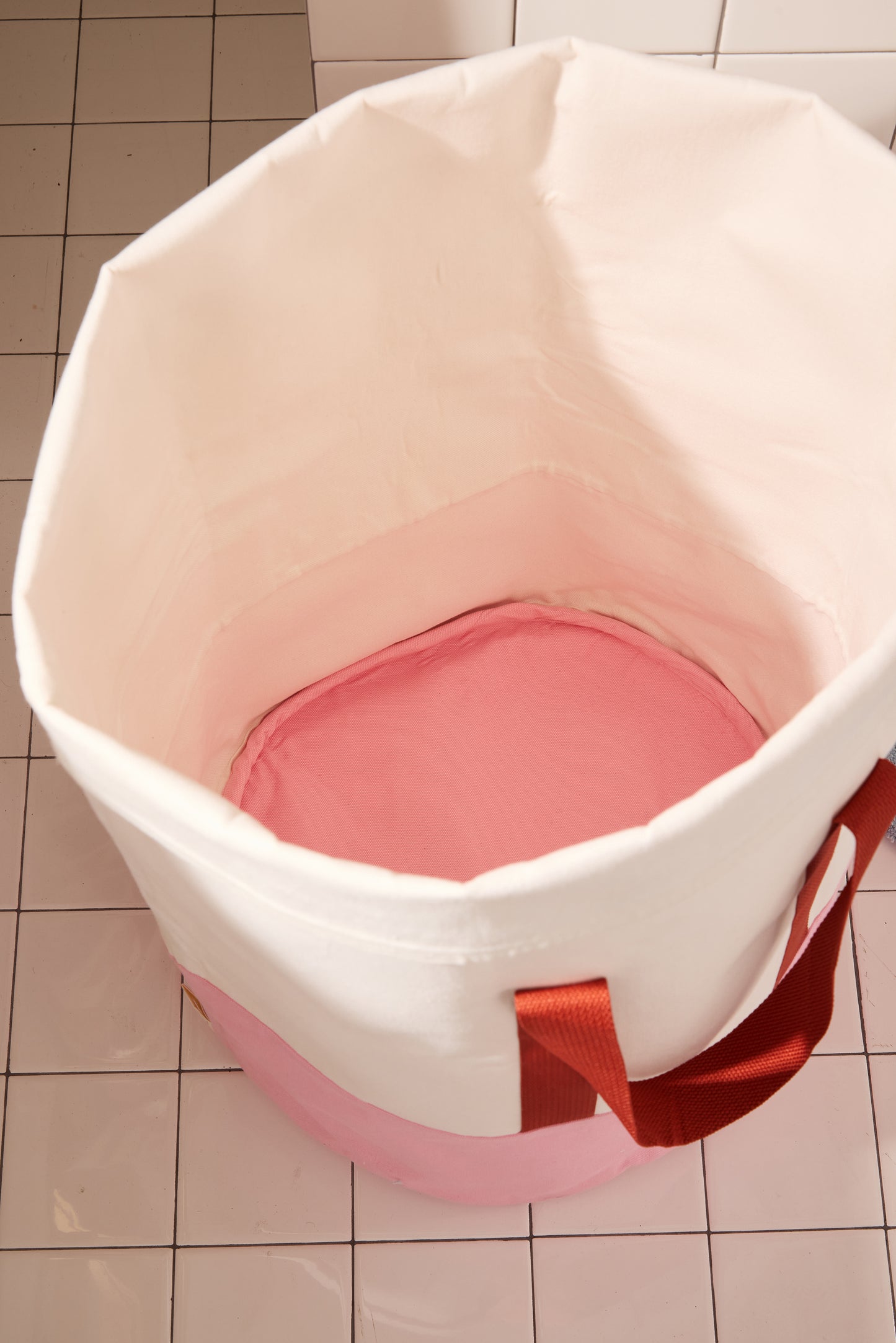 bottom of pink laundry bin on white tile floor