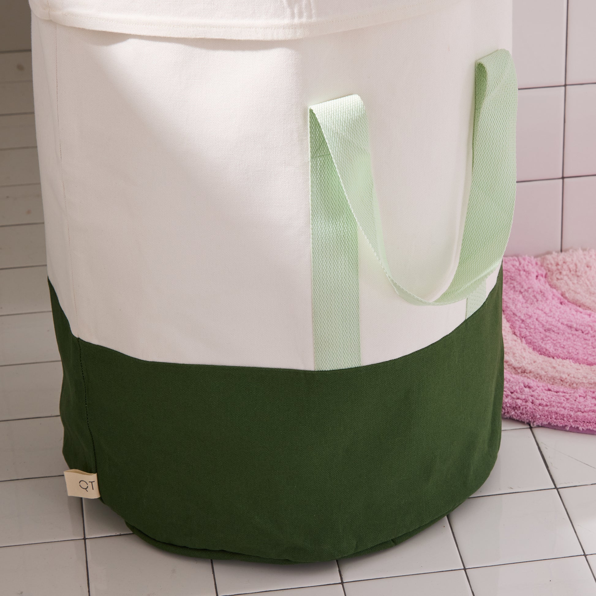 green and cream laundry hamper in white tiled bathroom