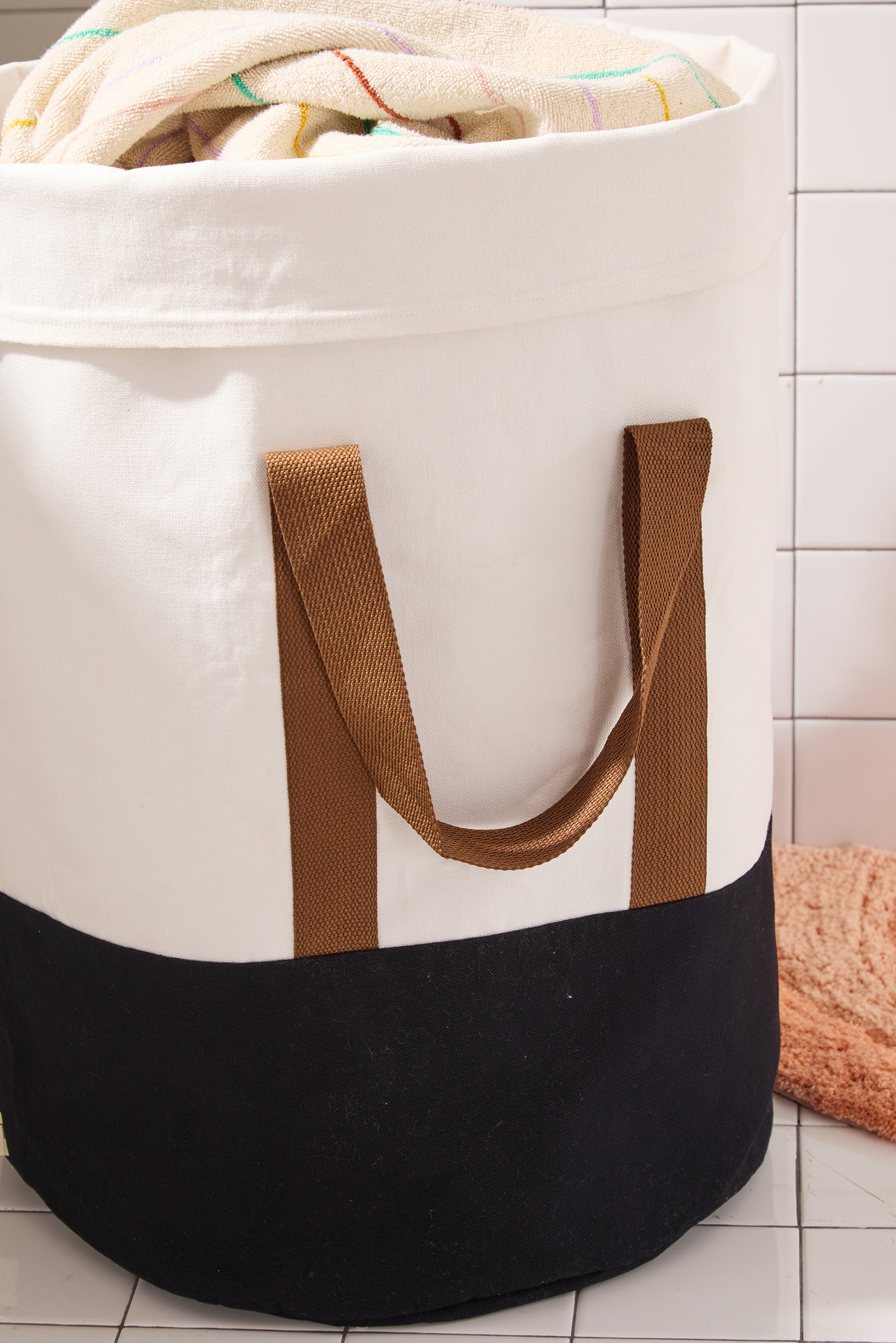cream hamper wtih black bottom and brown straps