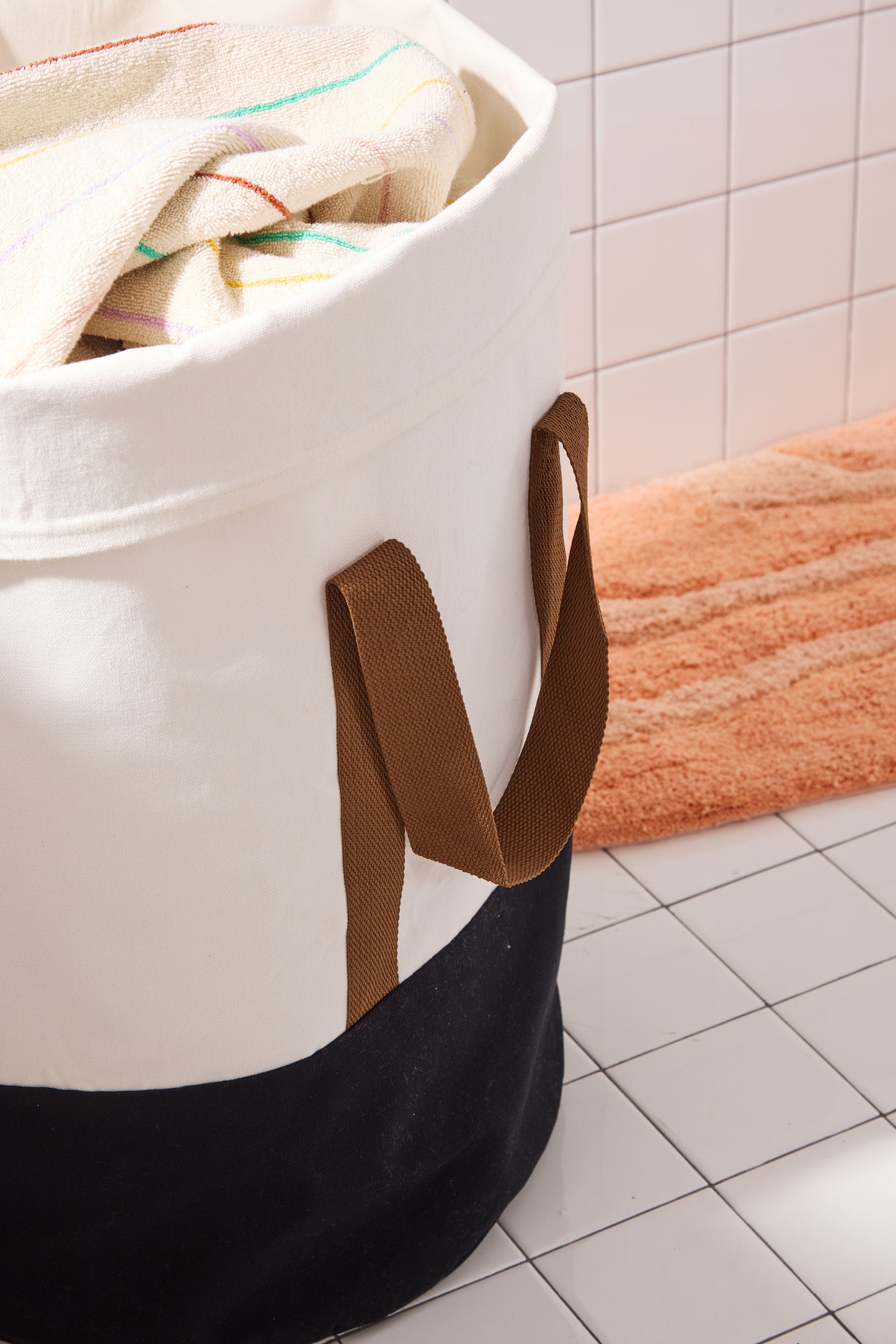 side of laundry hamper with brown straps and black bottom. 