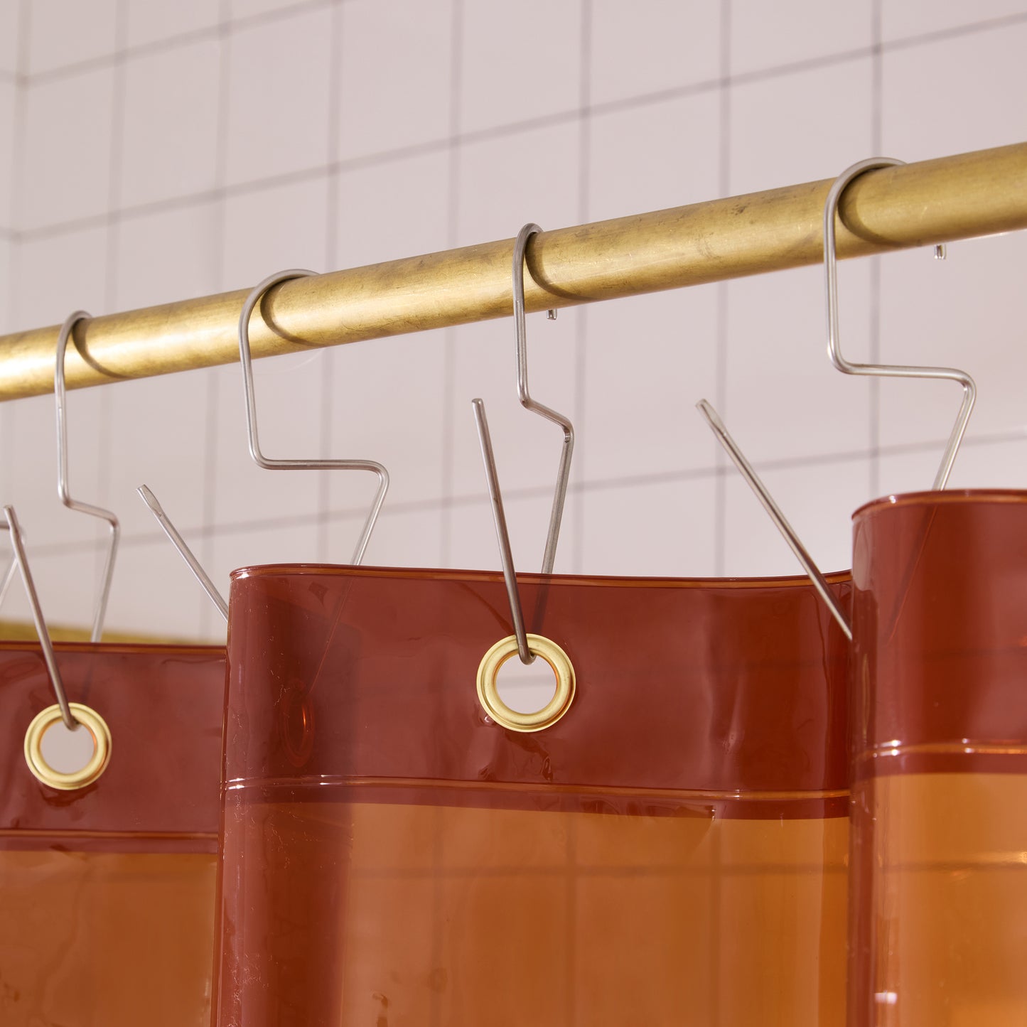 Top seam of orient sun shower curtain hanging on brass rod with silver venice hooks. 