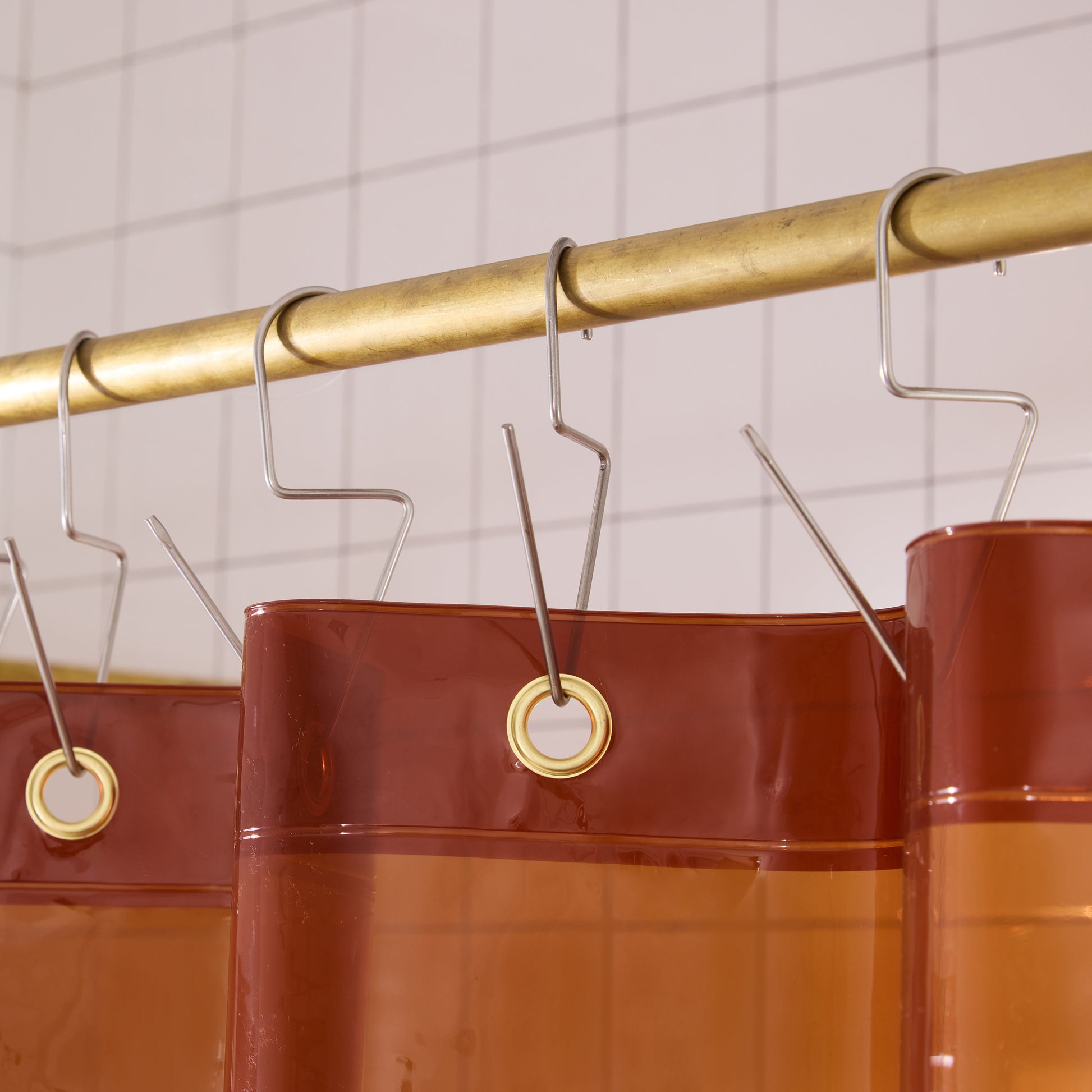 Top seam of orient sun shower curtain hanging on brass rod with silver venice hooks. 