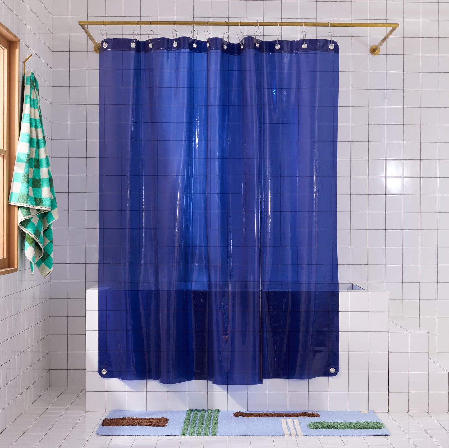 Sun Shower Navy front view of curtain hanging in a white tiled bathroom.