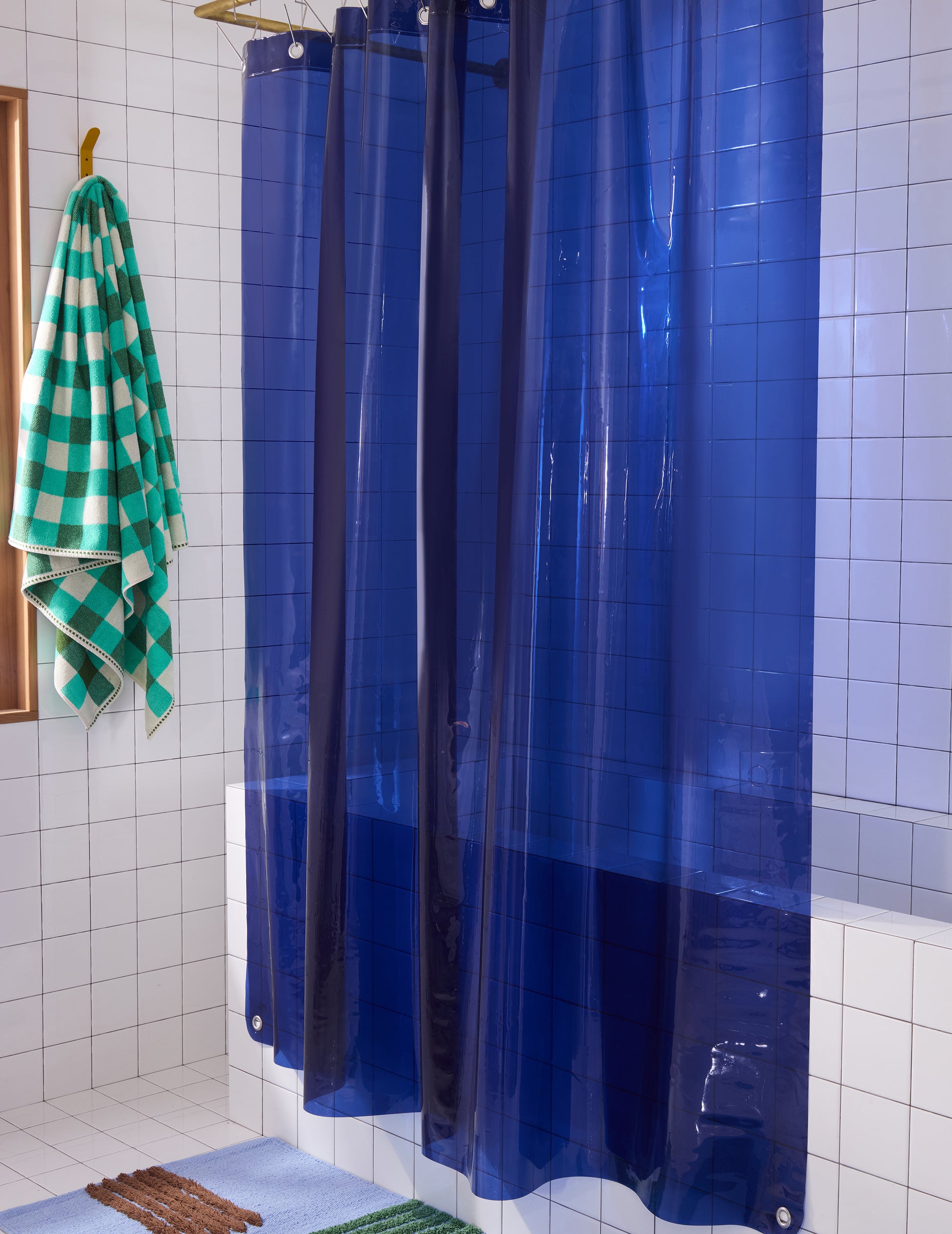 Side view of Sun shower navy curtain hanging in white tiled bathroom.