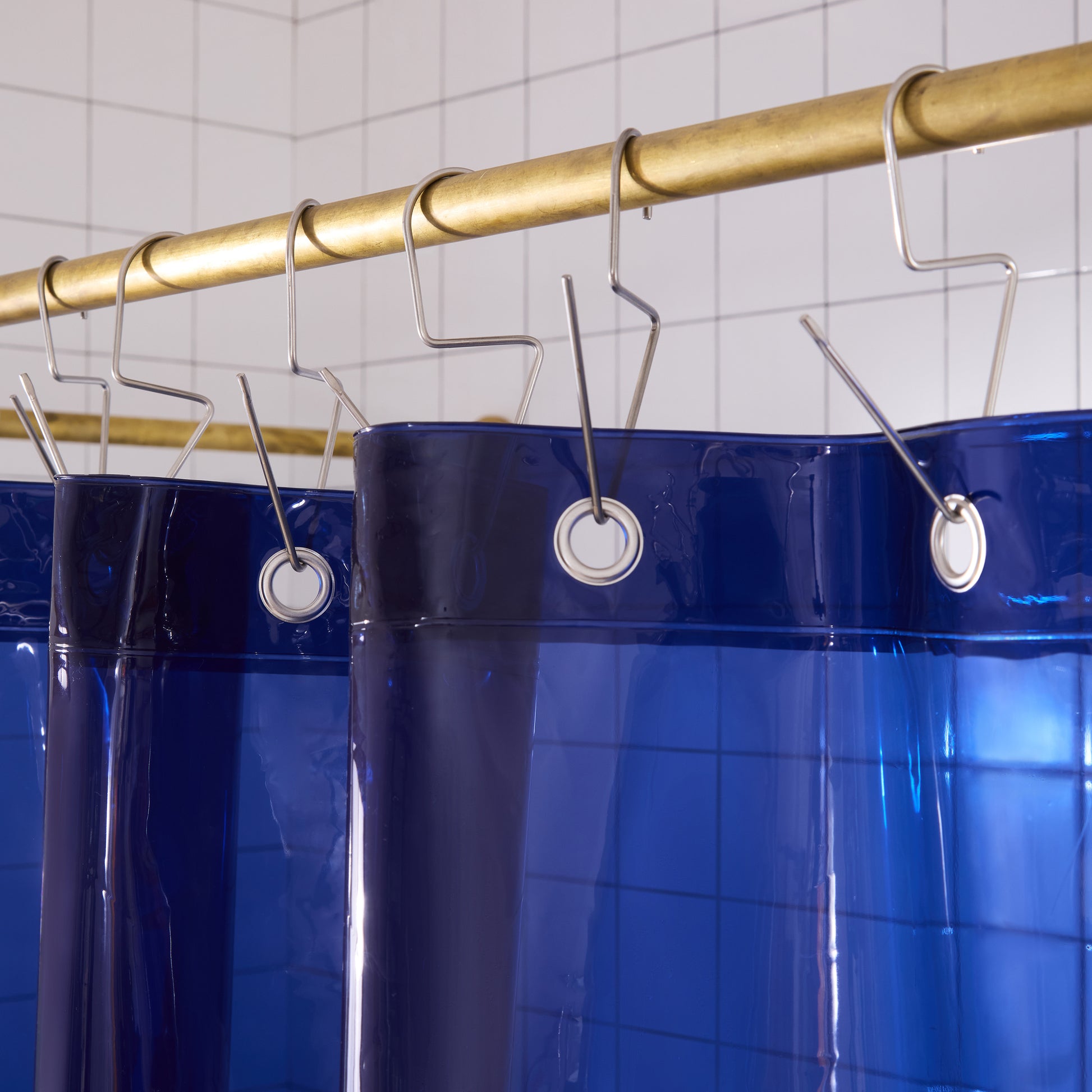 Top seam of sun shower navy curtain hanging on brass rod with silver venice hooks. 
