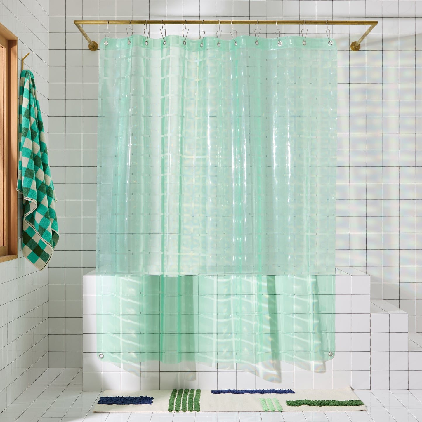 Mint colored shower curtain hangs in white tiled bathroom.