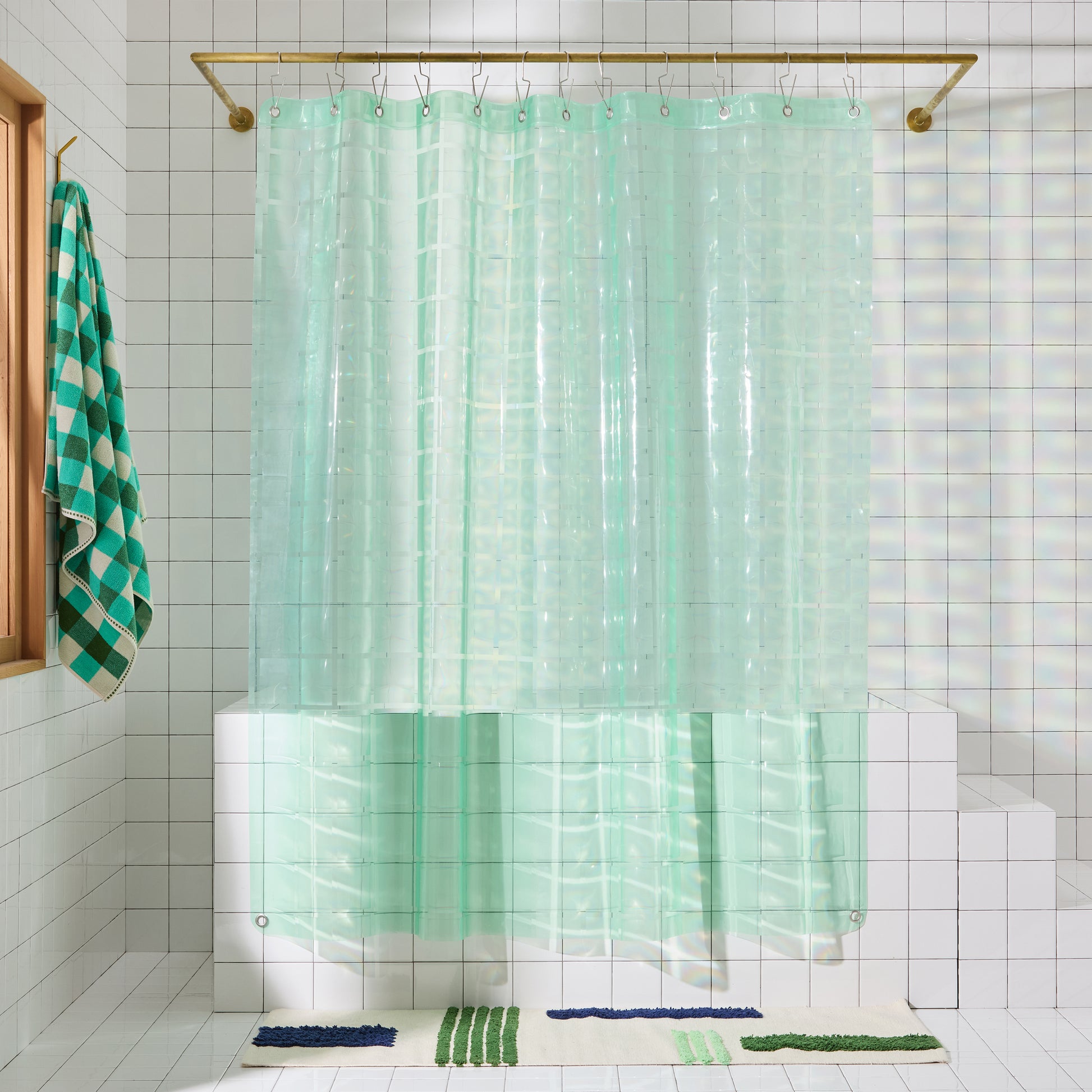 Mint colored shower curtain hangs in white tiled bathroom.