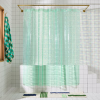 Mint colored shower curtain hangs in white tiled bathroom.