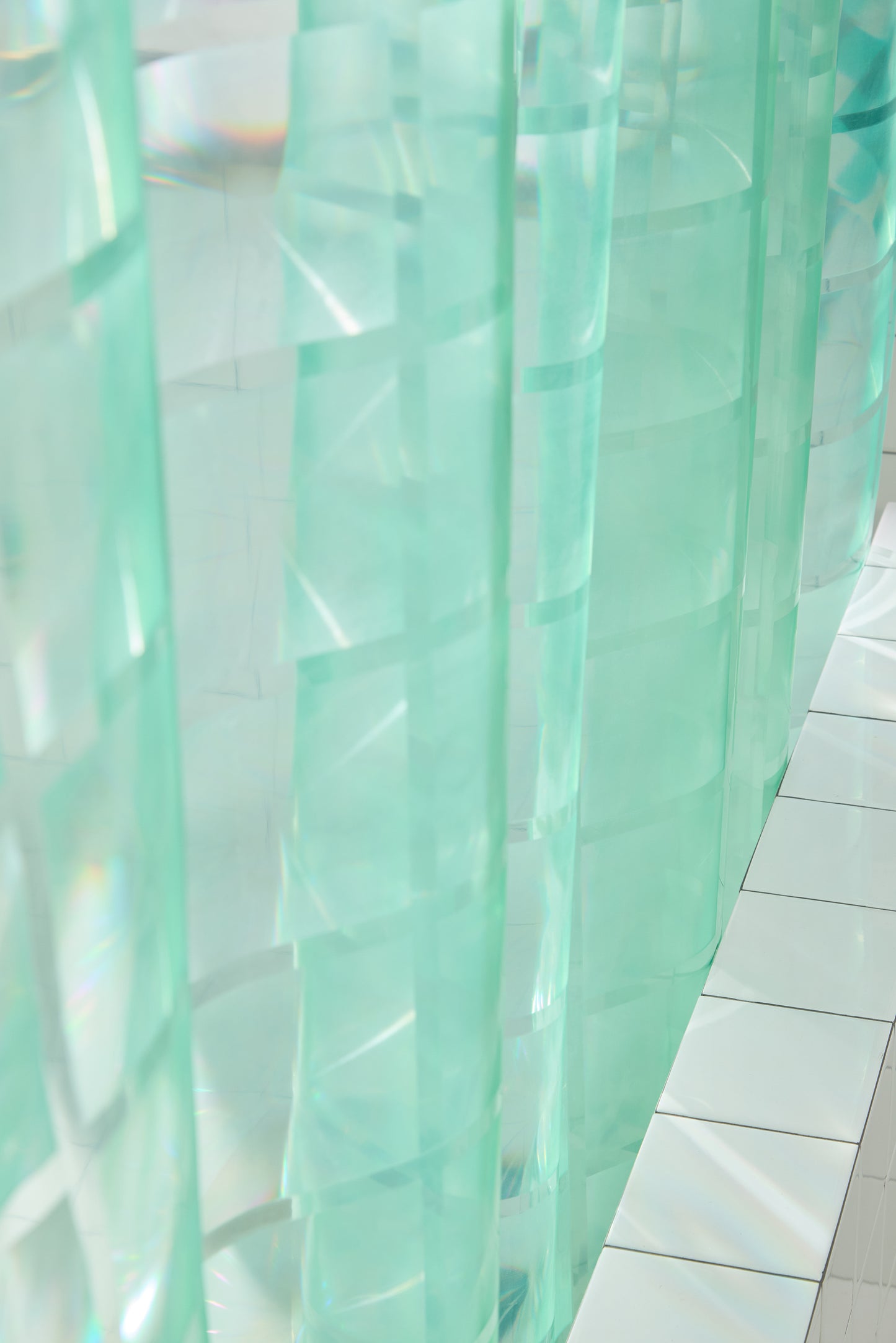 section of mint colored shower curtain with detail of embossed grout lines to look like glass bricks. 