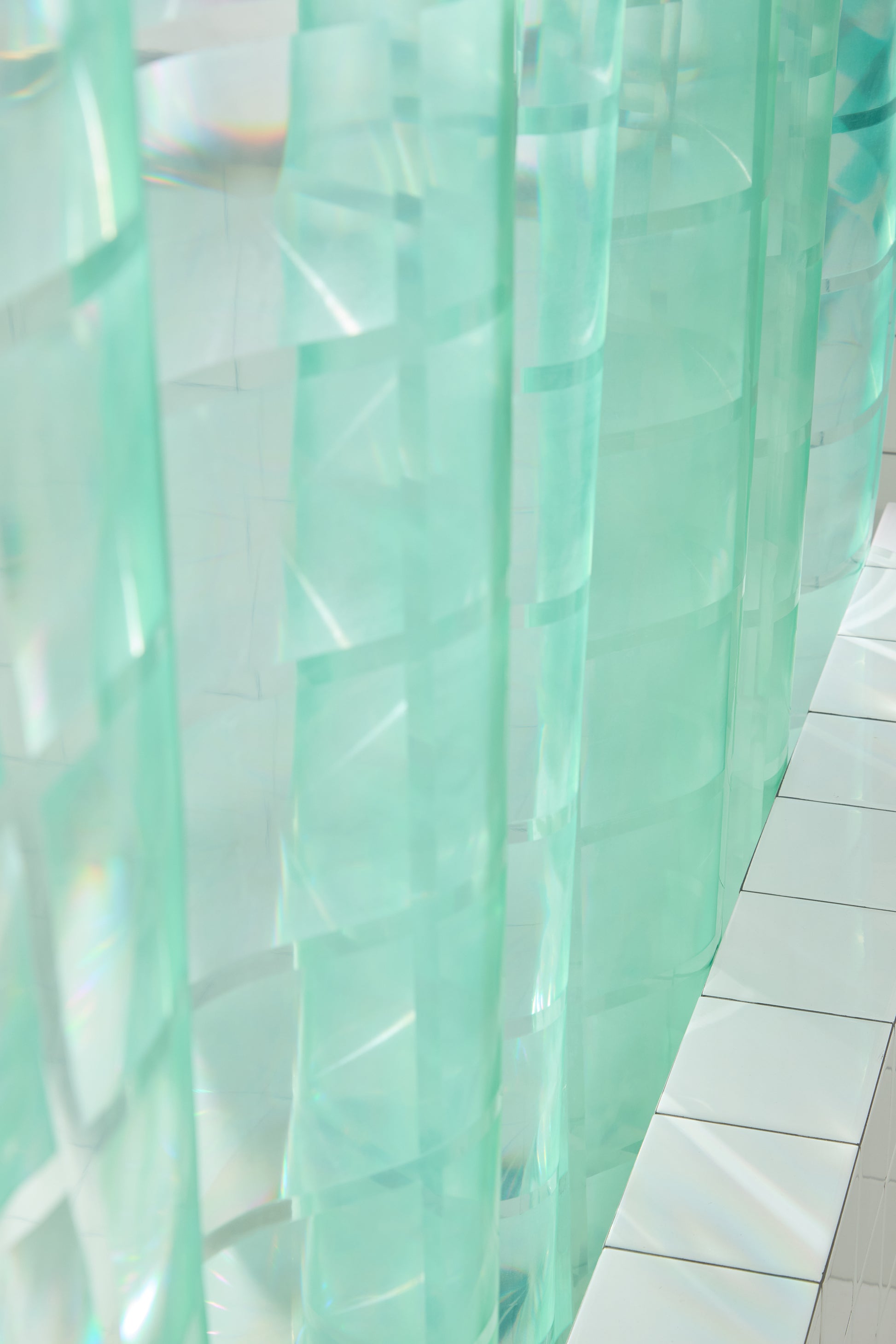 section of mint colored shower curtain with detail of embossed grout lines to look like glass bricks. 