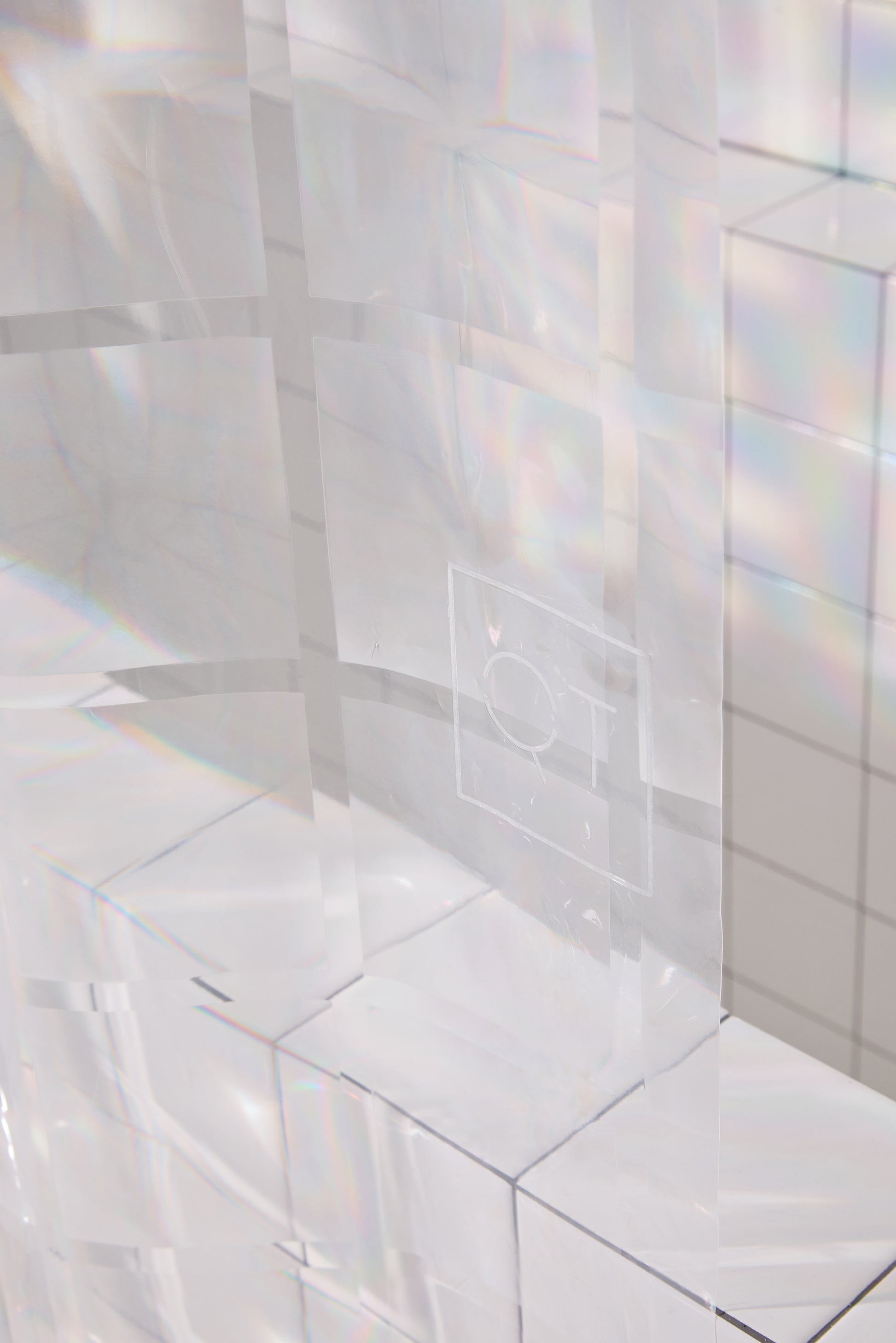 middle section of clear 3D curtain with QT logo in bathroom with white tile. 