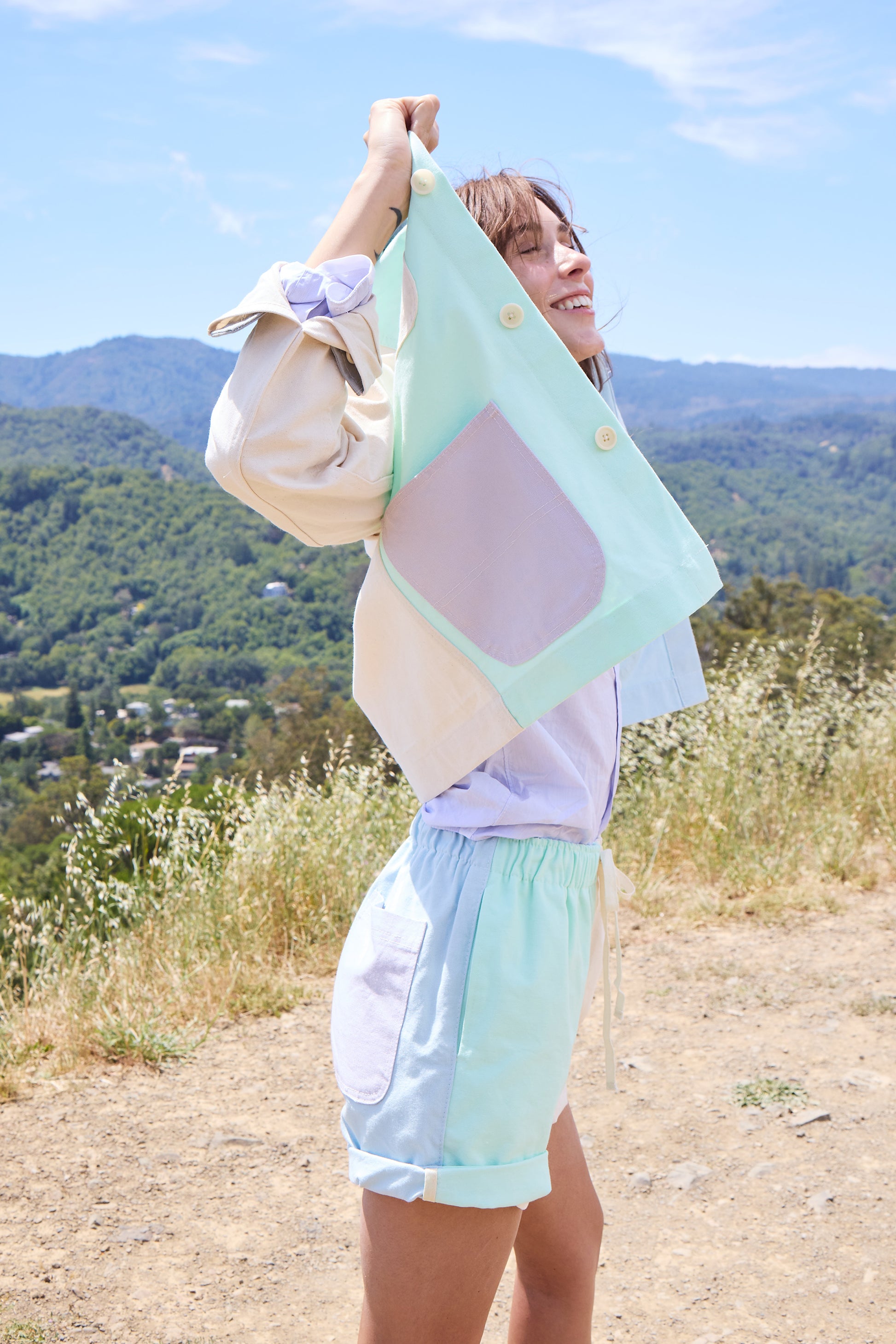 woman in a scenic landscape facing the side in colorful shorts and jacket. 