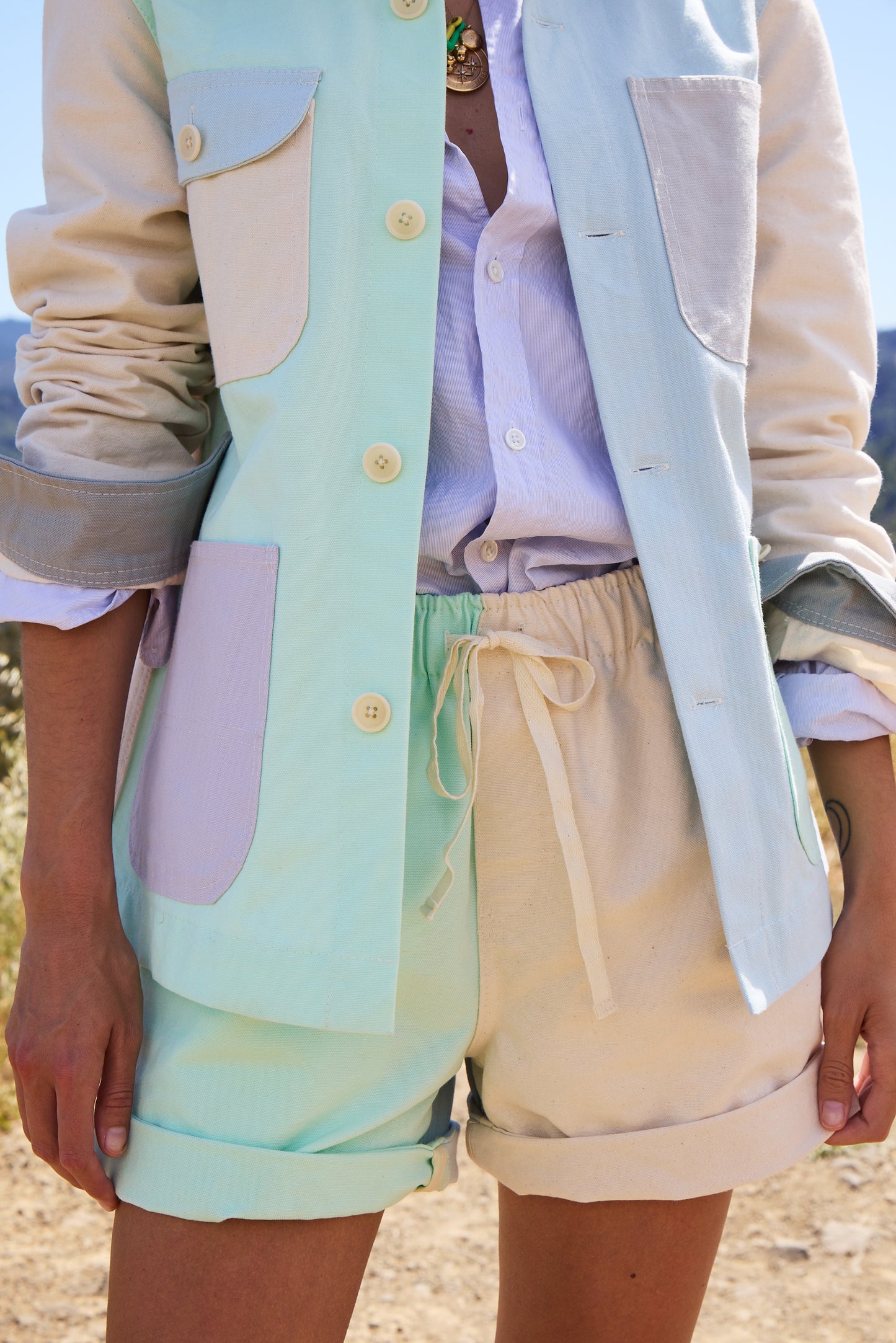 Person wearing a pastel-colored  jacket and shorts over a light shirt with colorblocked shorts.