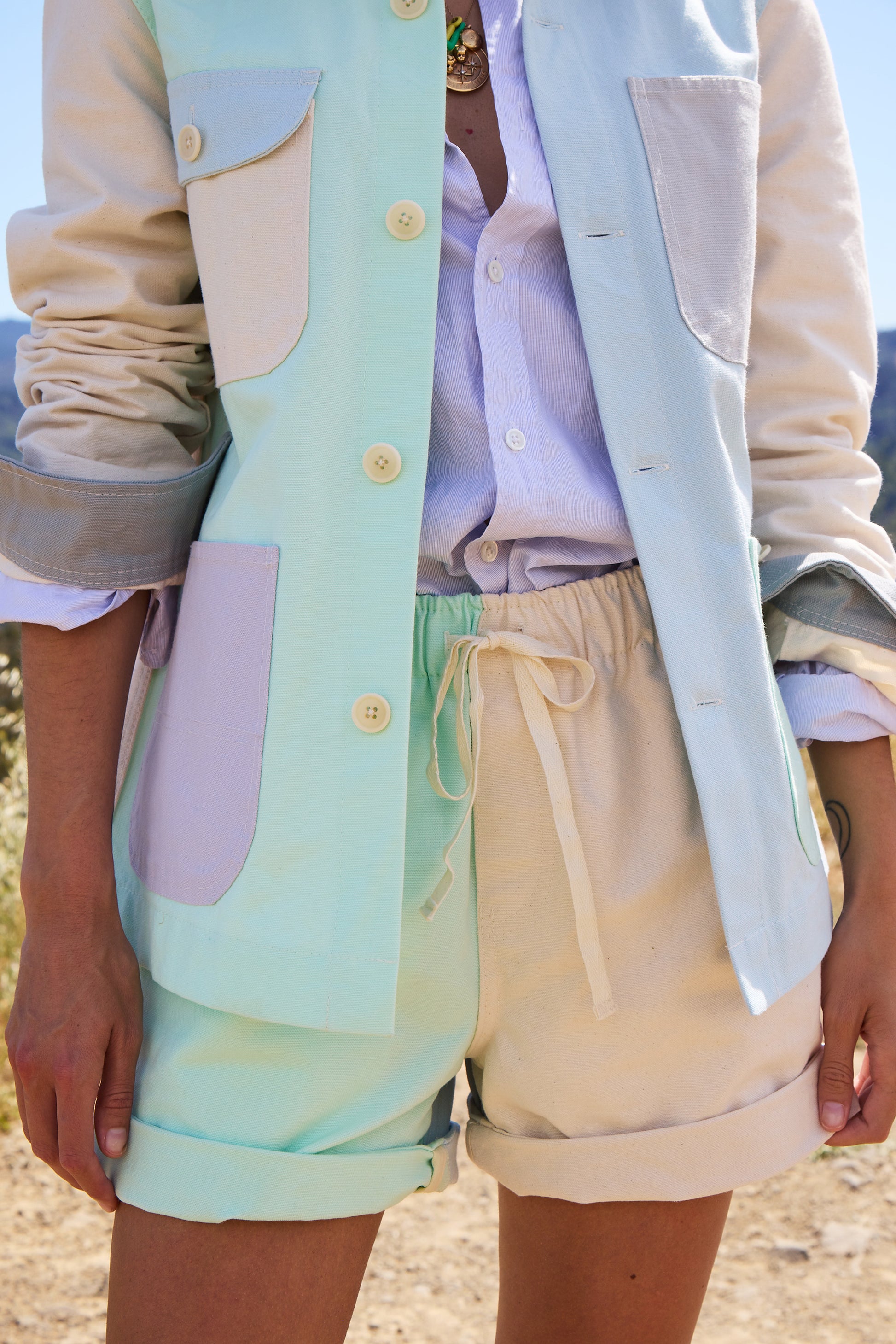 Person wearing a pastel-colored  jacket and shorts over a light shirt with colorblocked shorts.