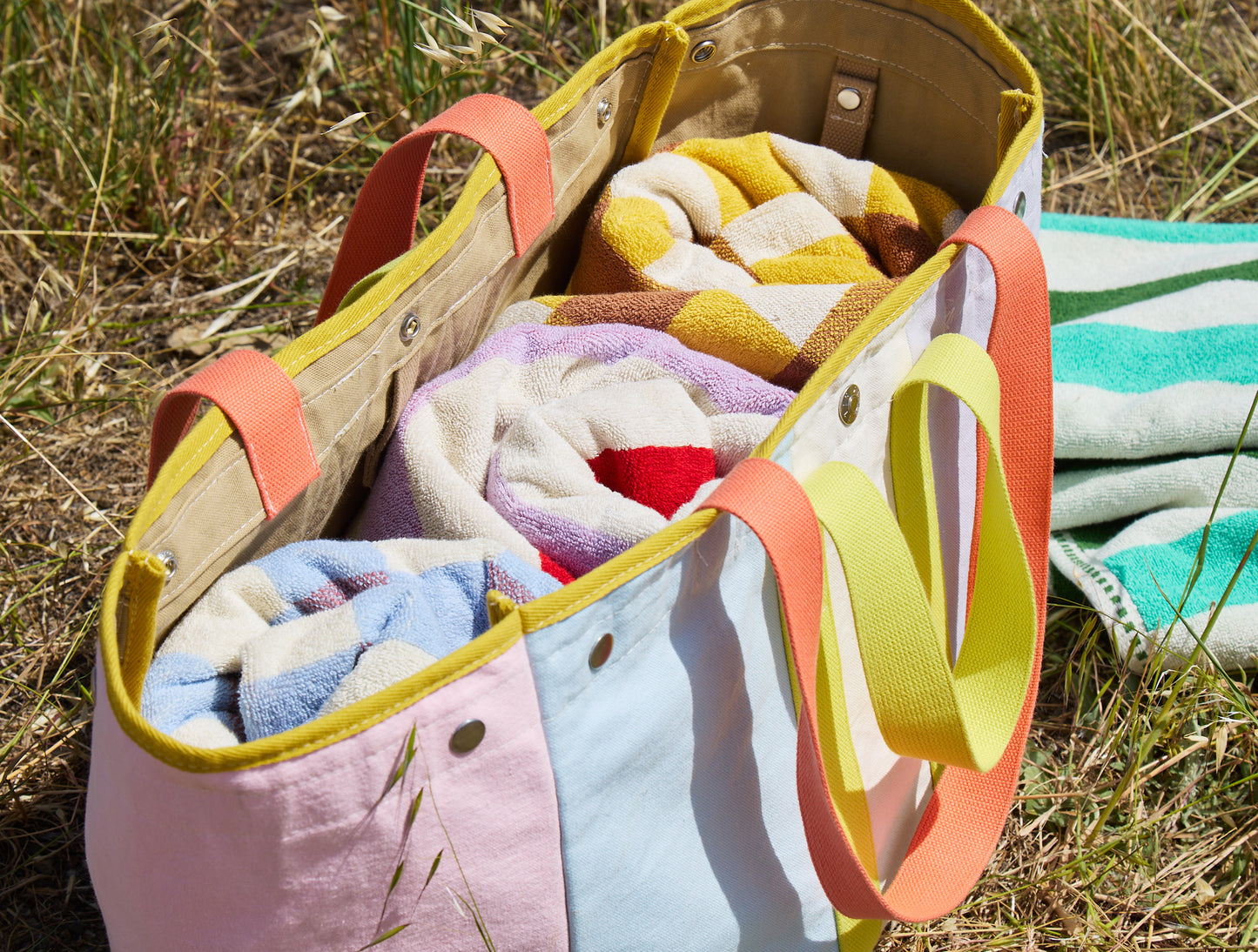 Colorful folded towels in a tote bag on grass