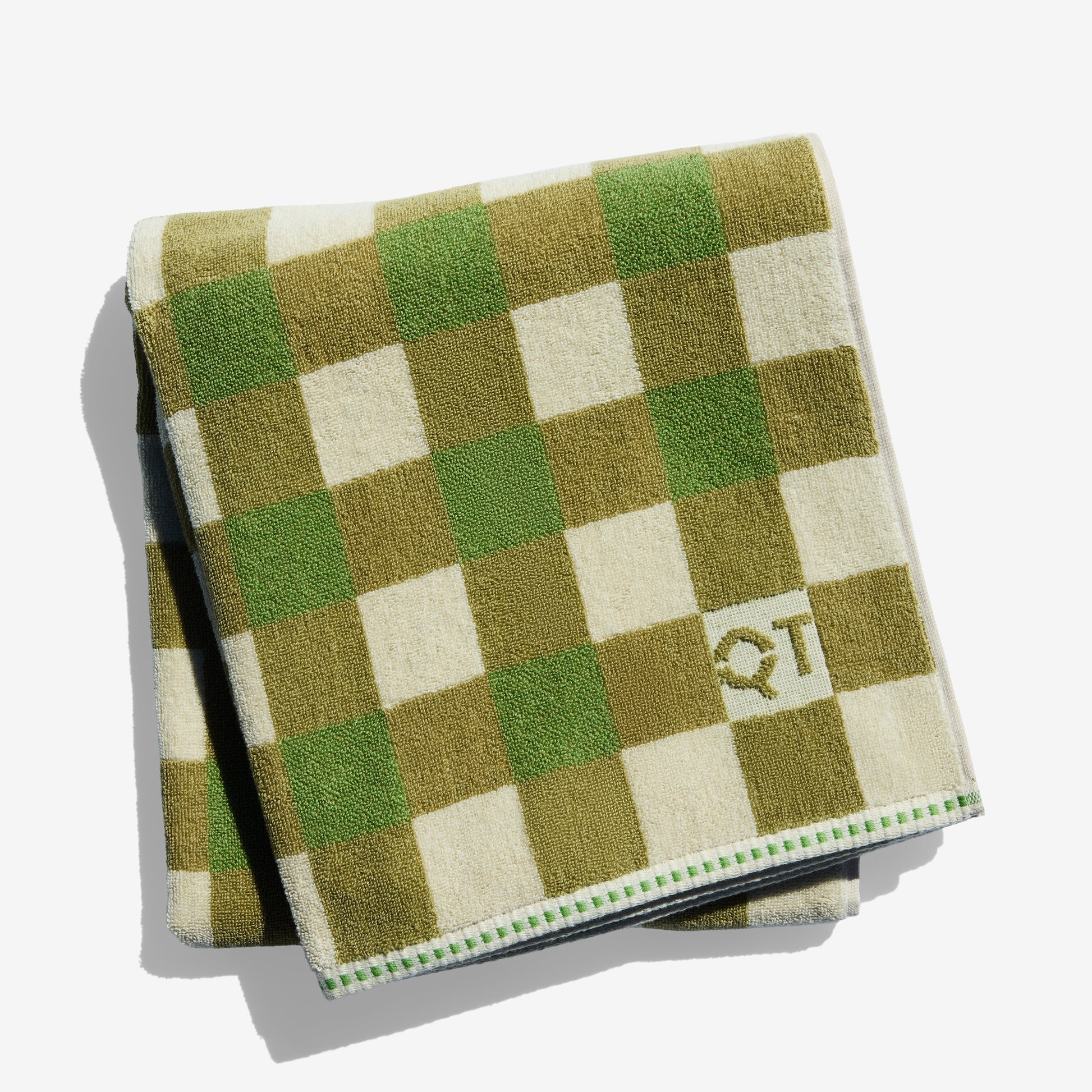 Checkered towel with green and olive and cream pattern on a white background