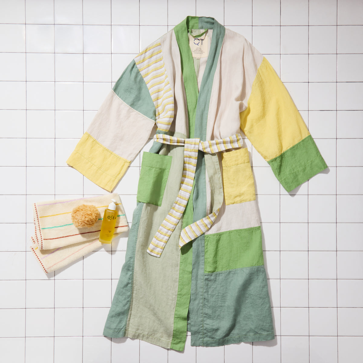 Green and yellow bathrobe with striped towel on a tiled floor