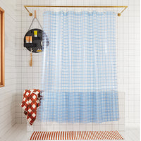 2x2 sun shower curtain in atlantic hanging in a white tiled bathroom. 