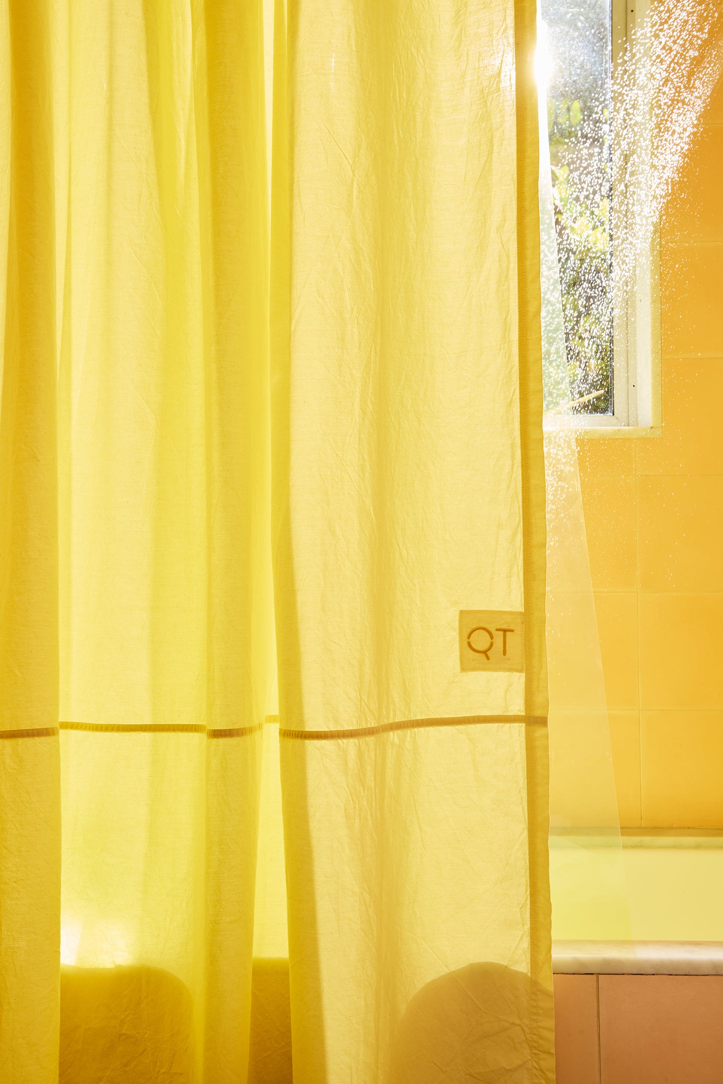 Yellow curtain with a QT logo in front of a window
