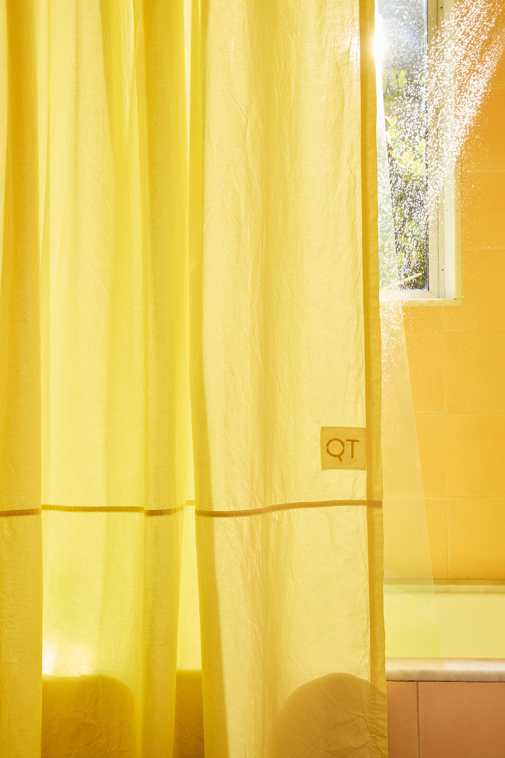Yellow curtain with a QT logo in front of a window