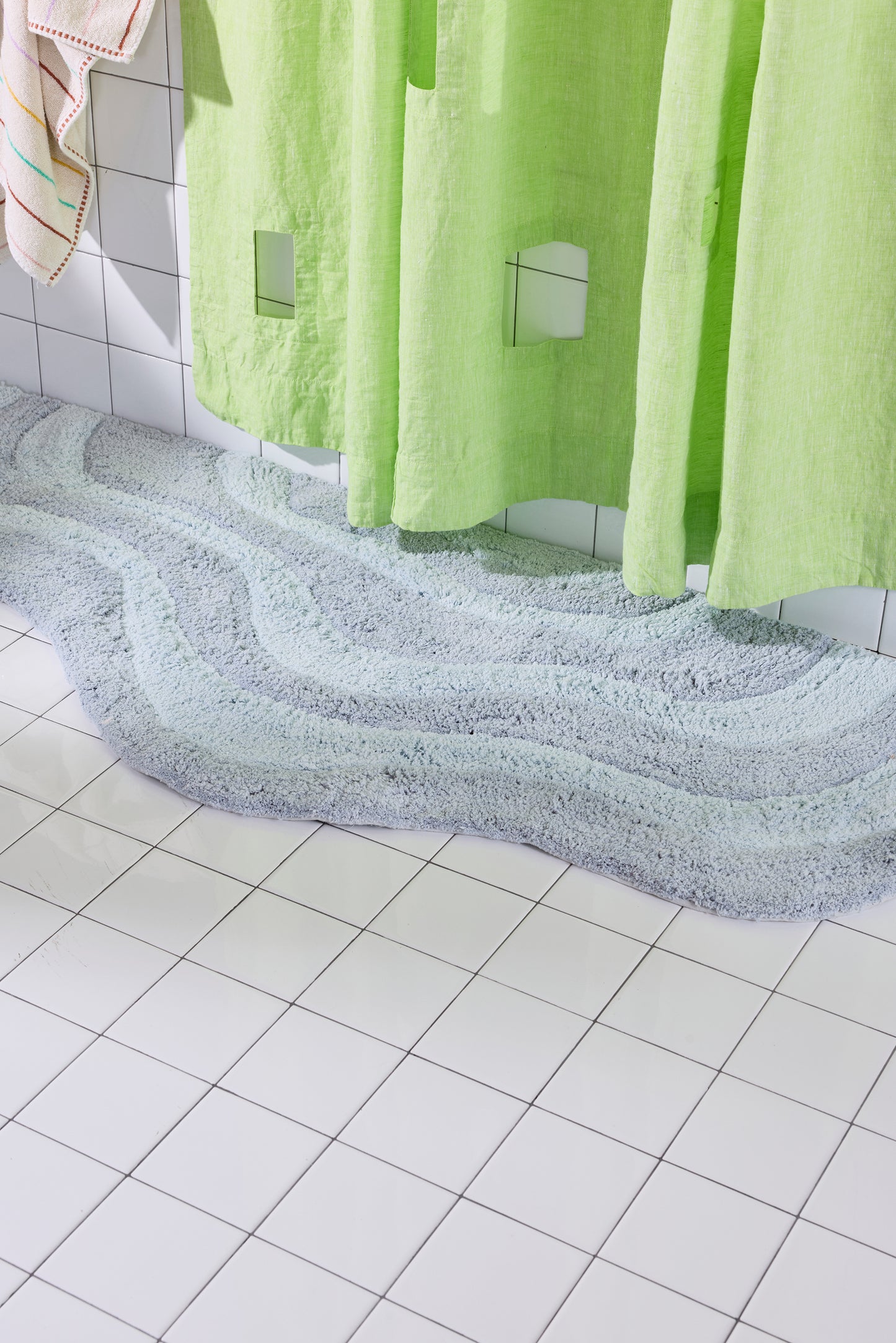 Green shower curtain with a textured floor and tiled wall in the background