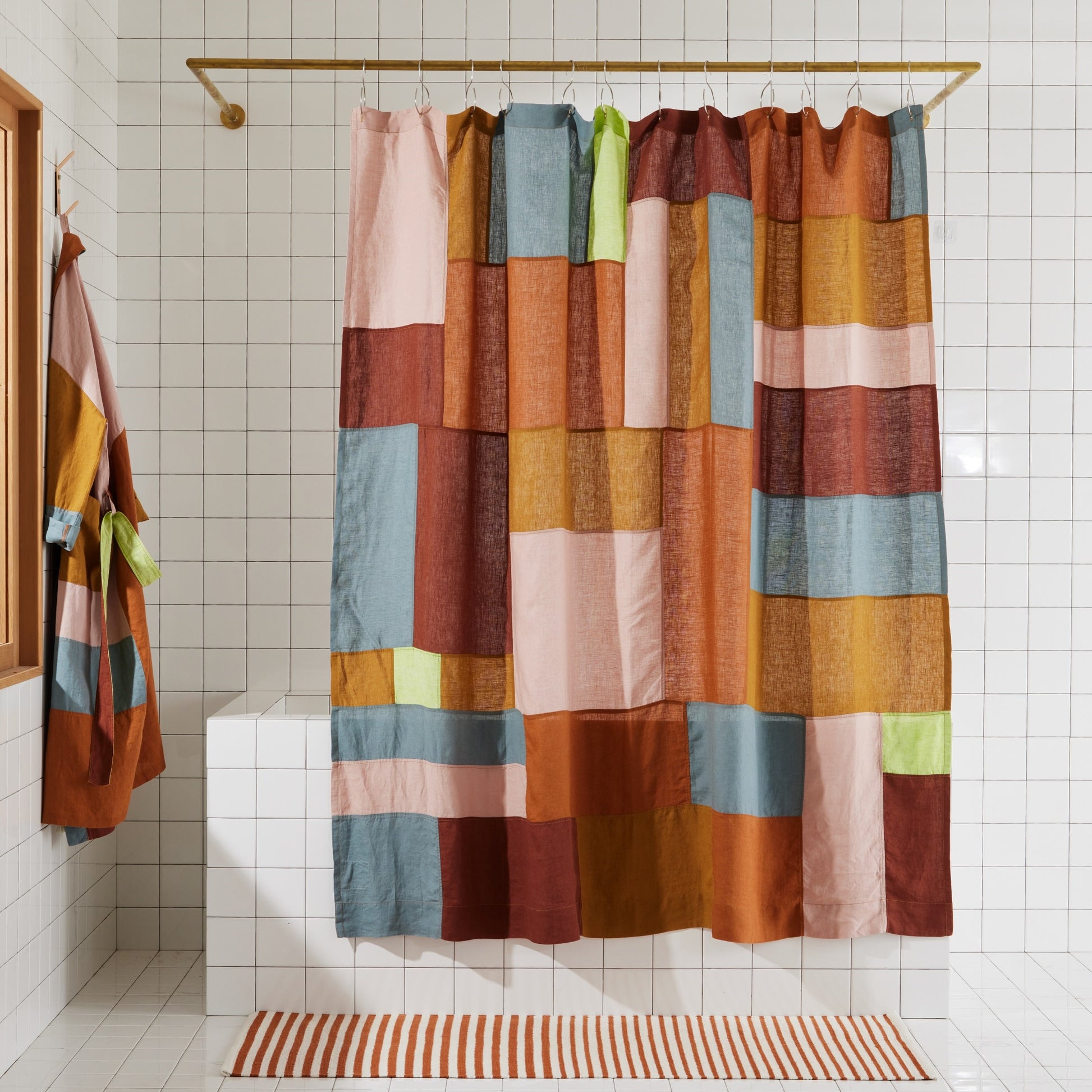 Multi-color linen shower curtain in rose hanging in white tiled bathroom. 