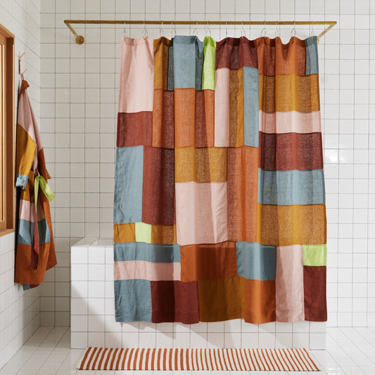 Multi-color linen shower curtain in rose hanging in white tiled bathroom. 