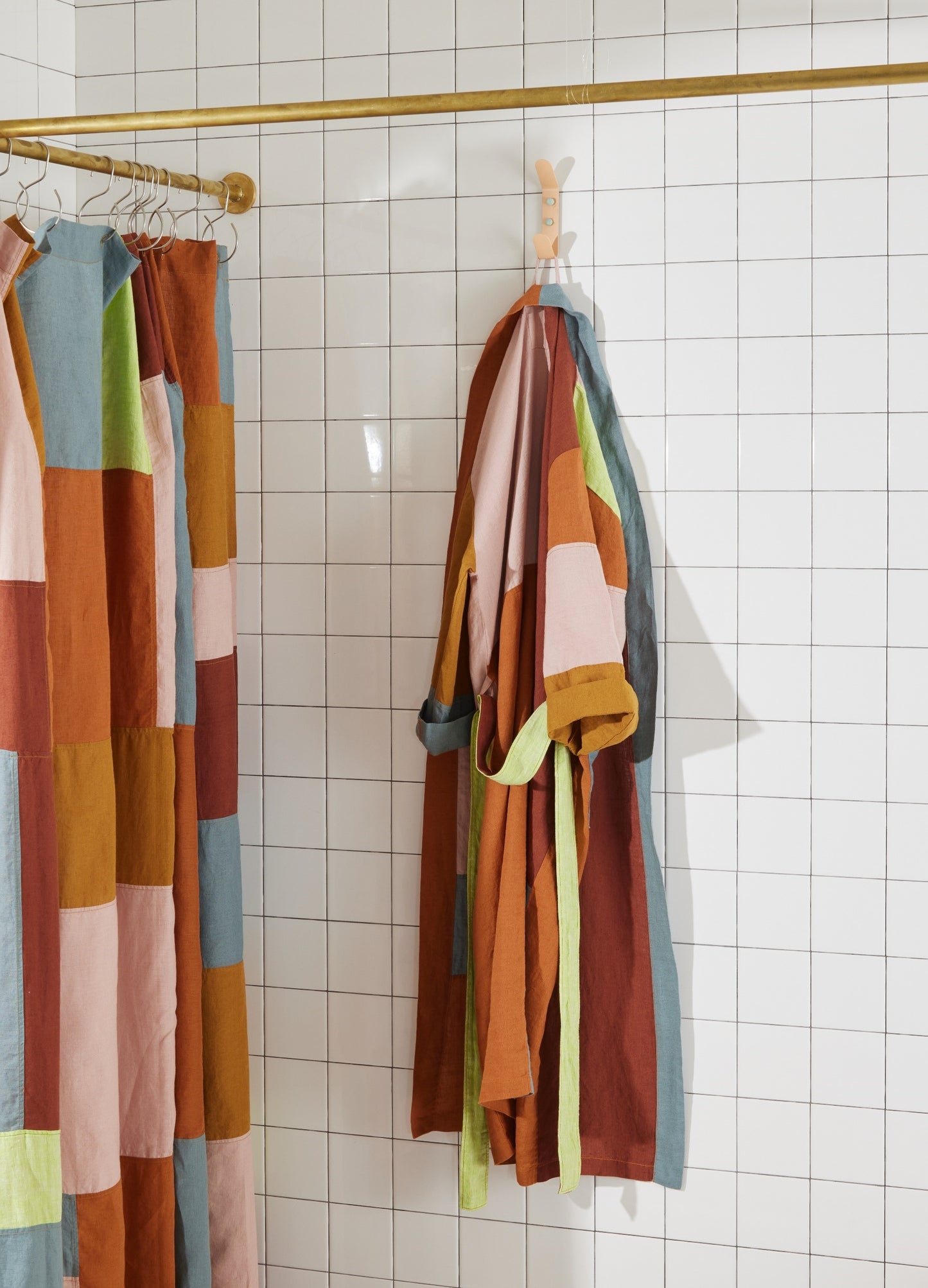 Side view of end bits linen shower curtain in rose styled next to matching end bits linen bath robe in rose.