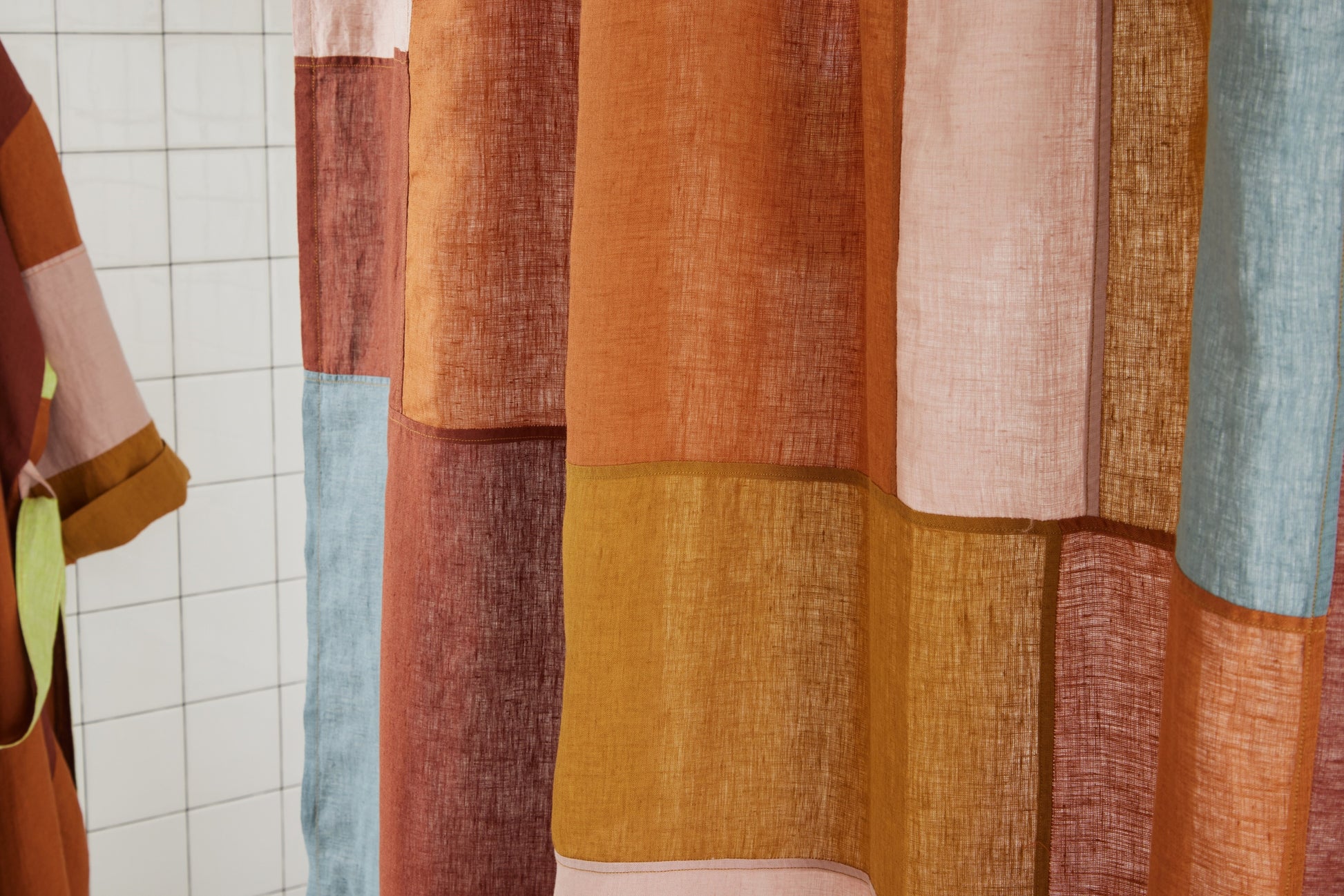 Detail view of multi-color linen shower curtain featuring warm-toned linen patchwork pattern.